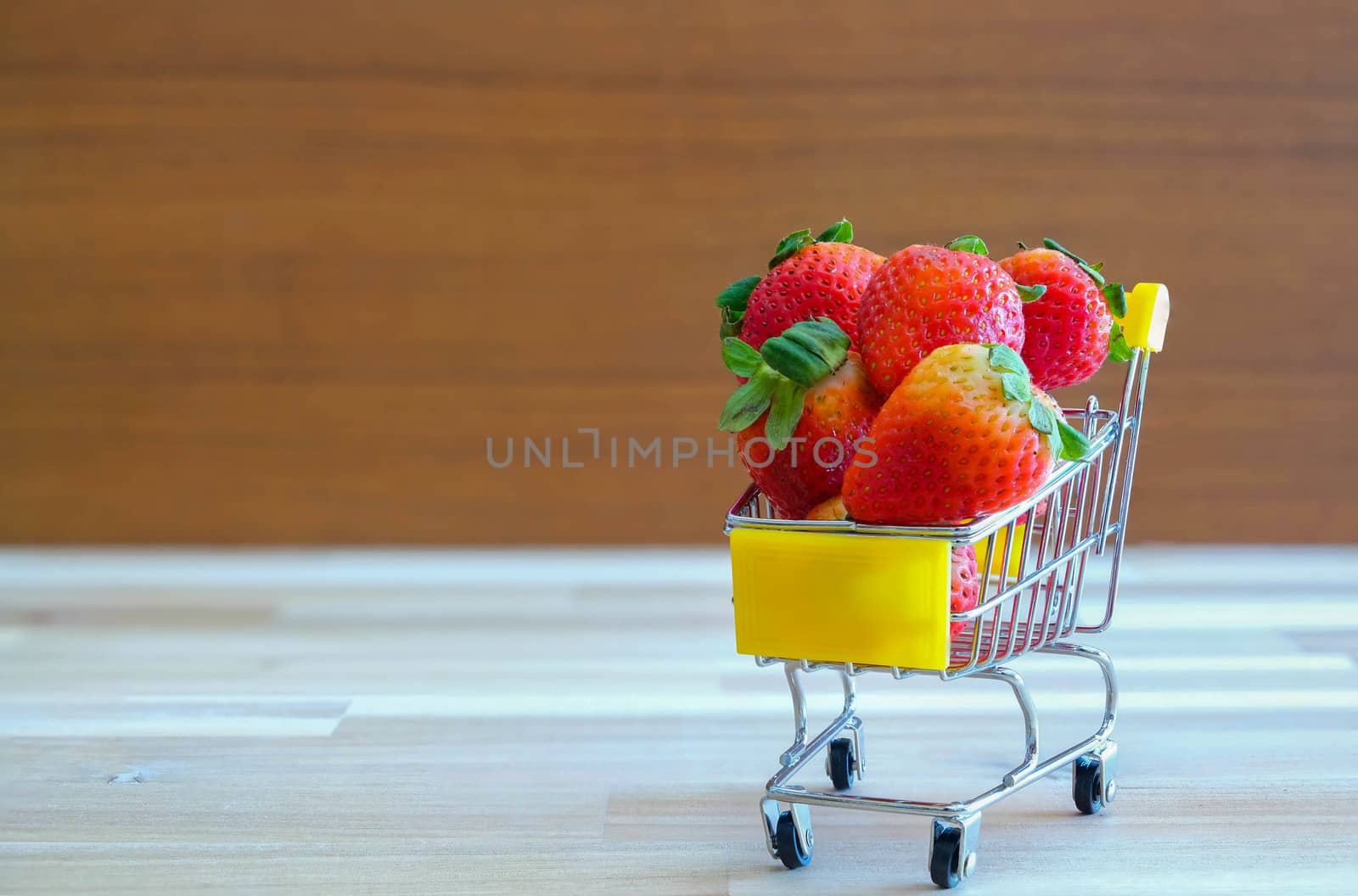 Close up strawberry on shopping cart with white and brown wooden background,text advertising, diet food healthy food