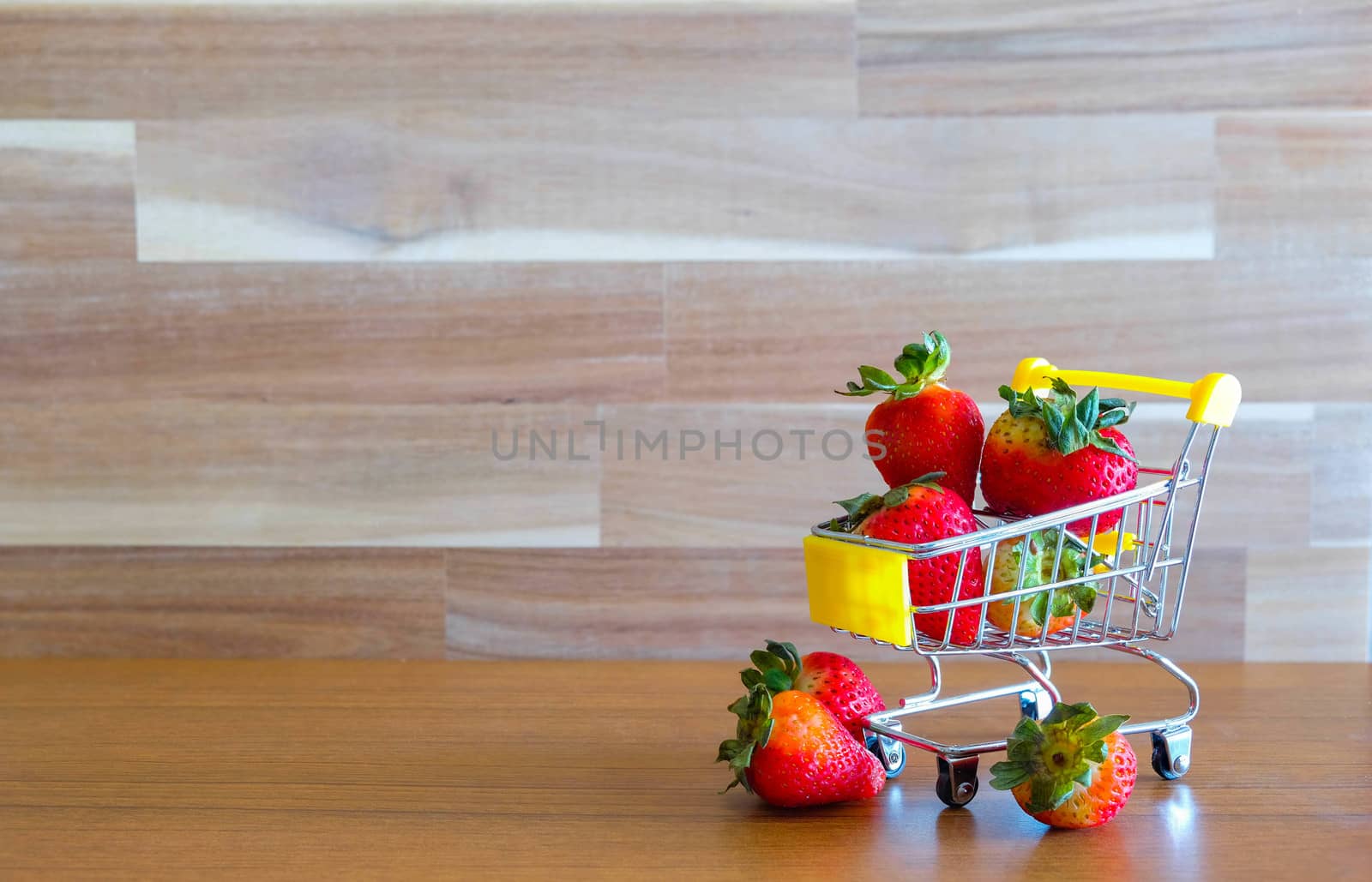 Close up strawberry on shopping cart with white and brown wooden background text advertising, diet food healthy food