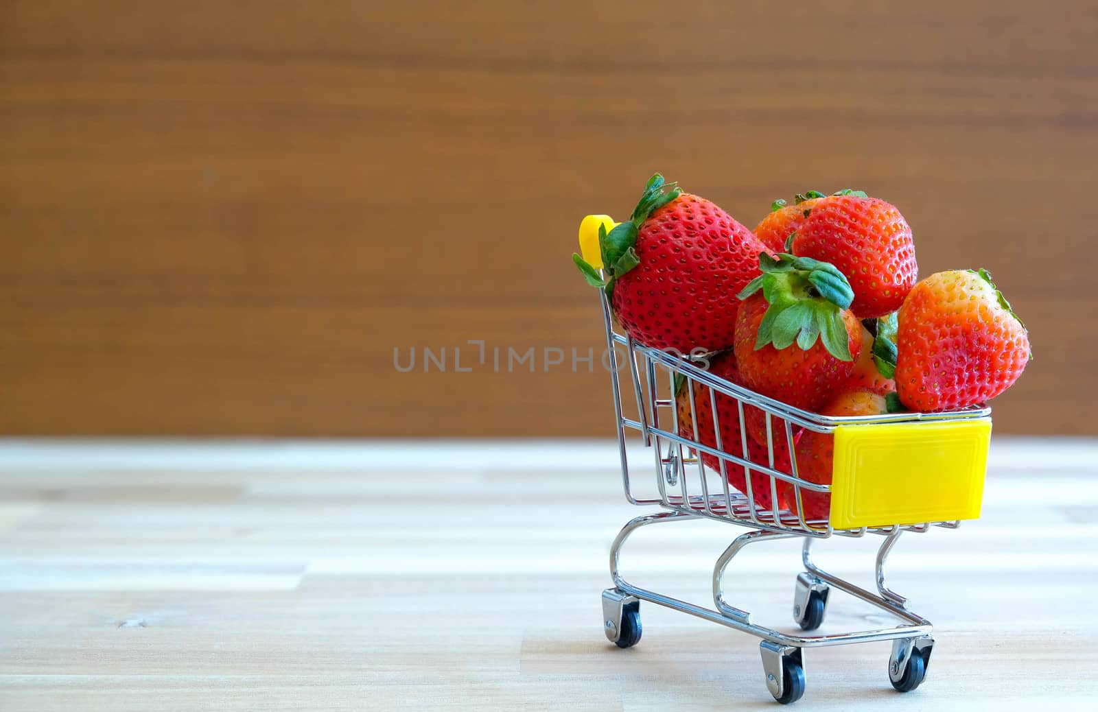 Close up strawberry on shopping cart with white and brown wooden background,text advertising, diet food healthy food