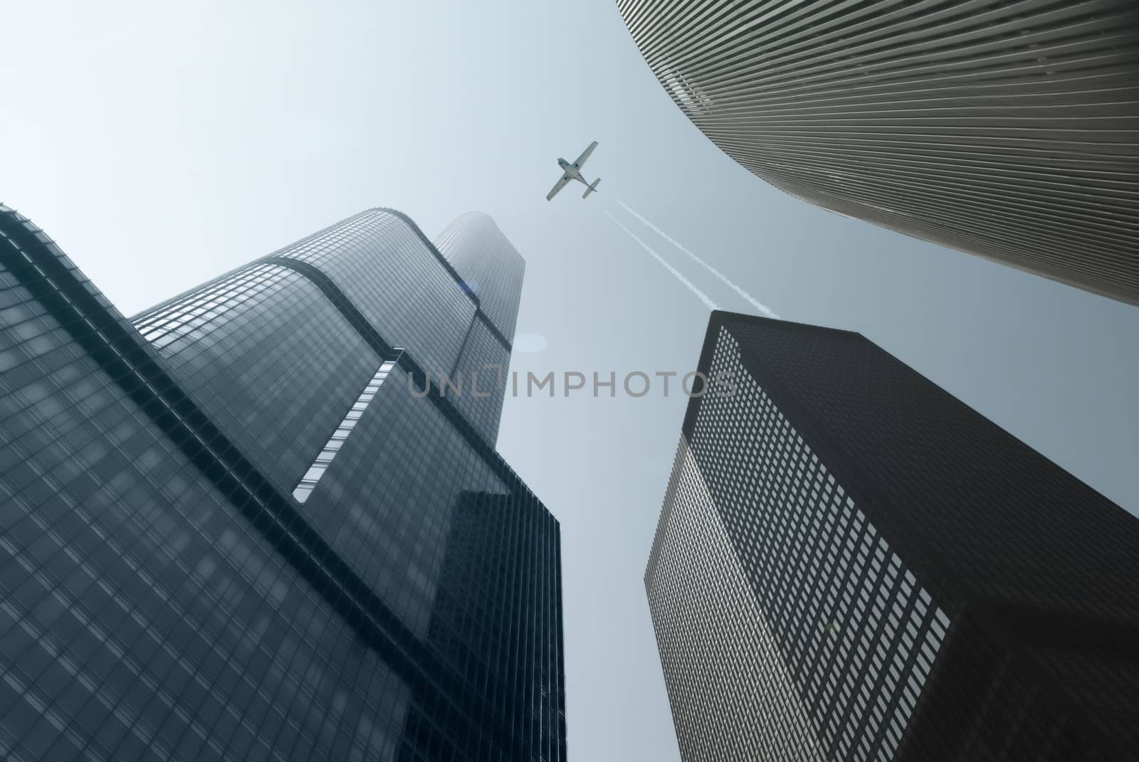 Modern Skyscrapers And Single Engine Plane With Trails Over Blue Sky