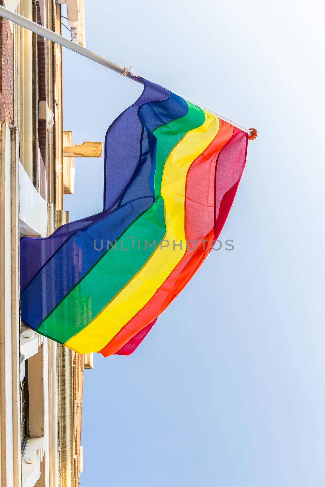Amsterdam Pride festival rainbow flag hanging from canal house on Keizersgracht viewed from below