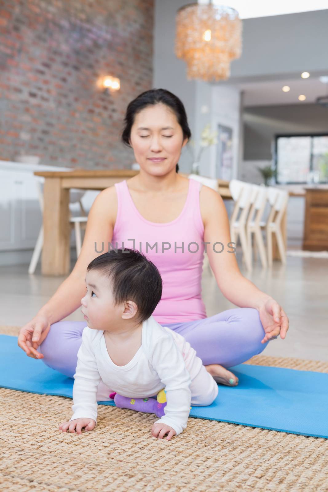 Calm mother meditating on mat at home by Wavebreakmedia