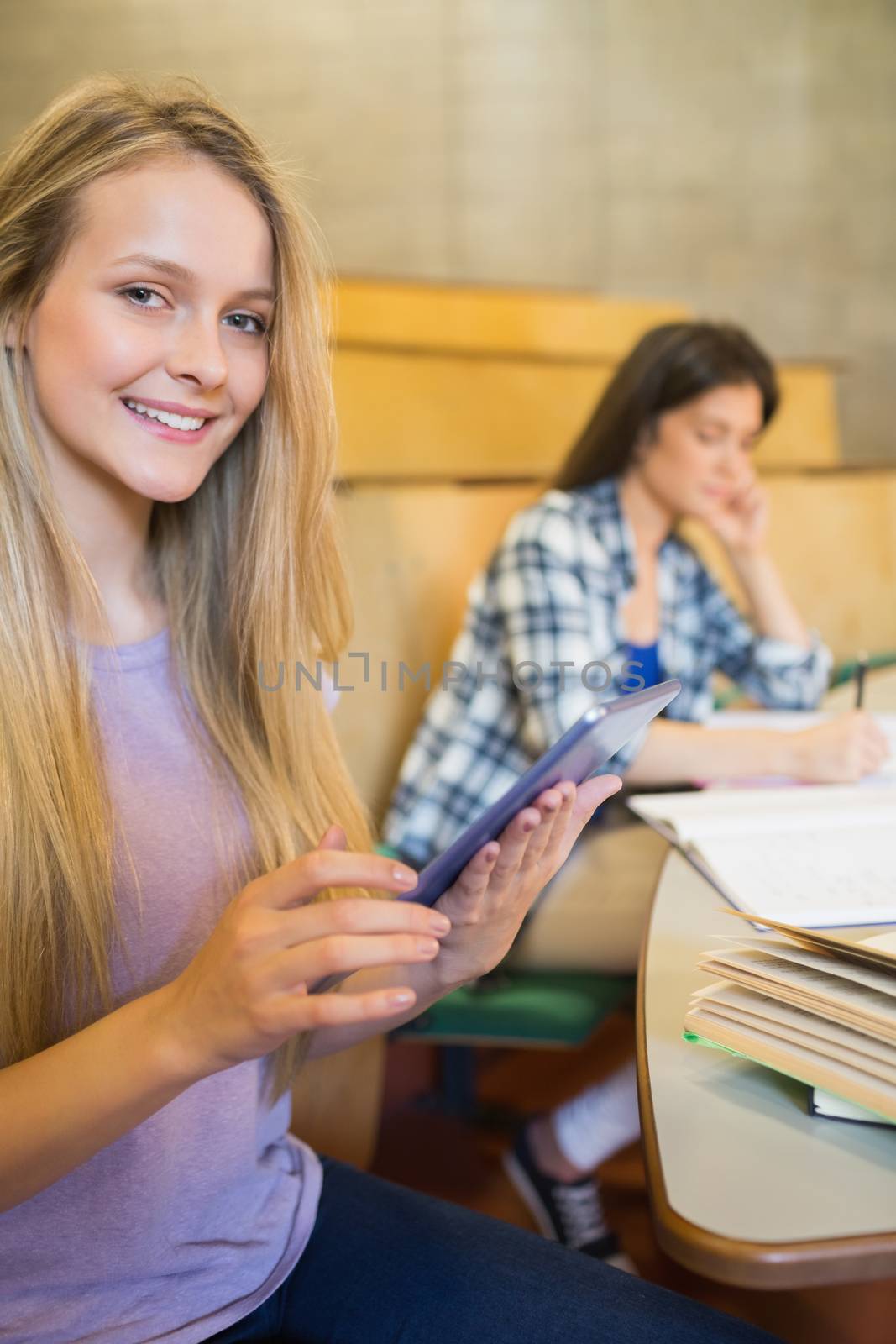 Pretty blonde student using tablet in university