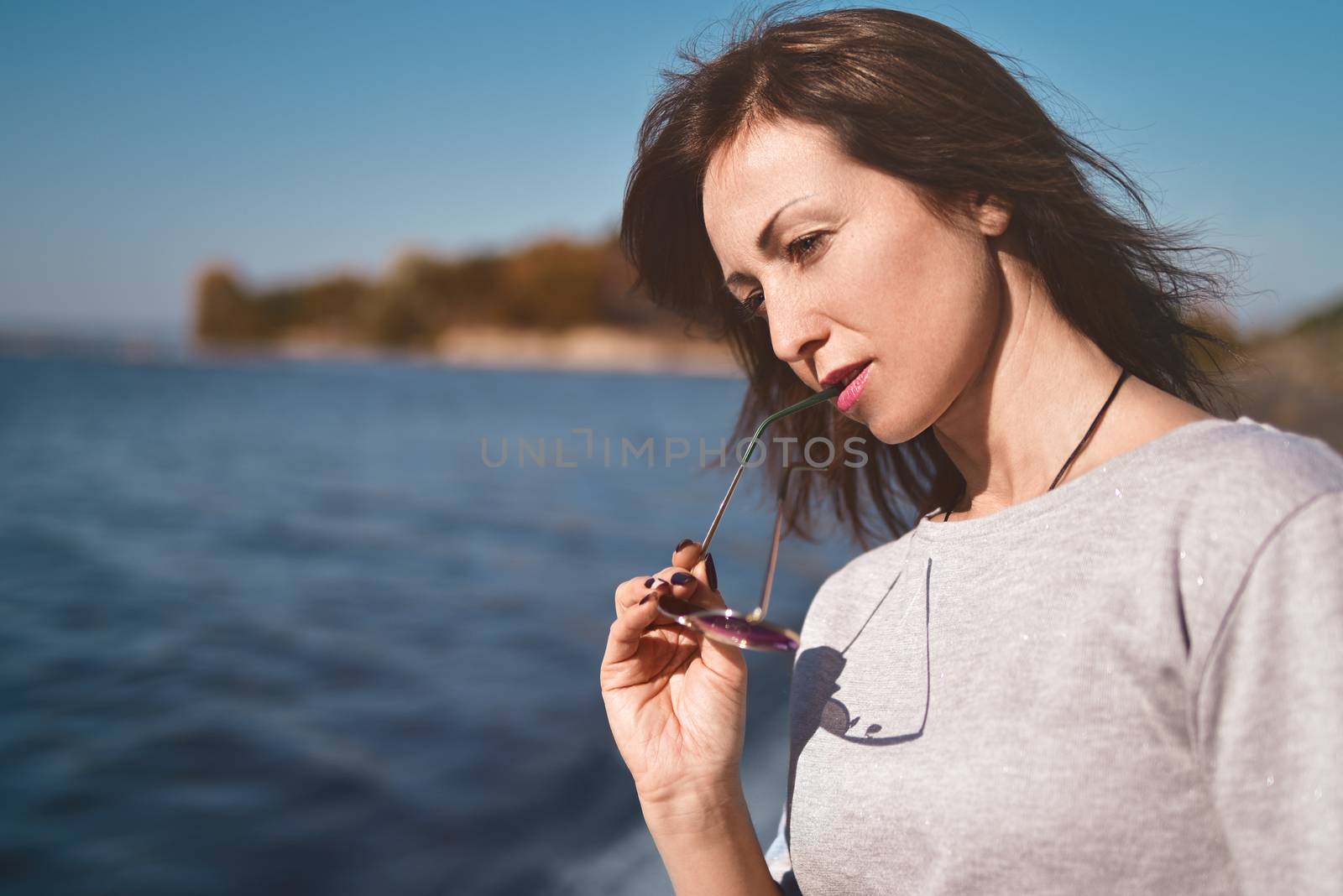 Fine art portrait of a beautiful adult woman on the sea river on the pier