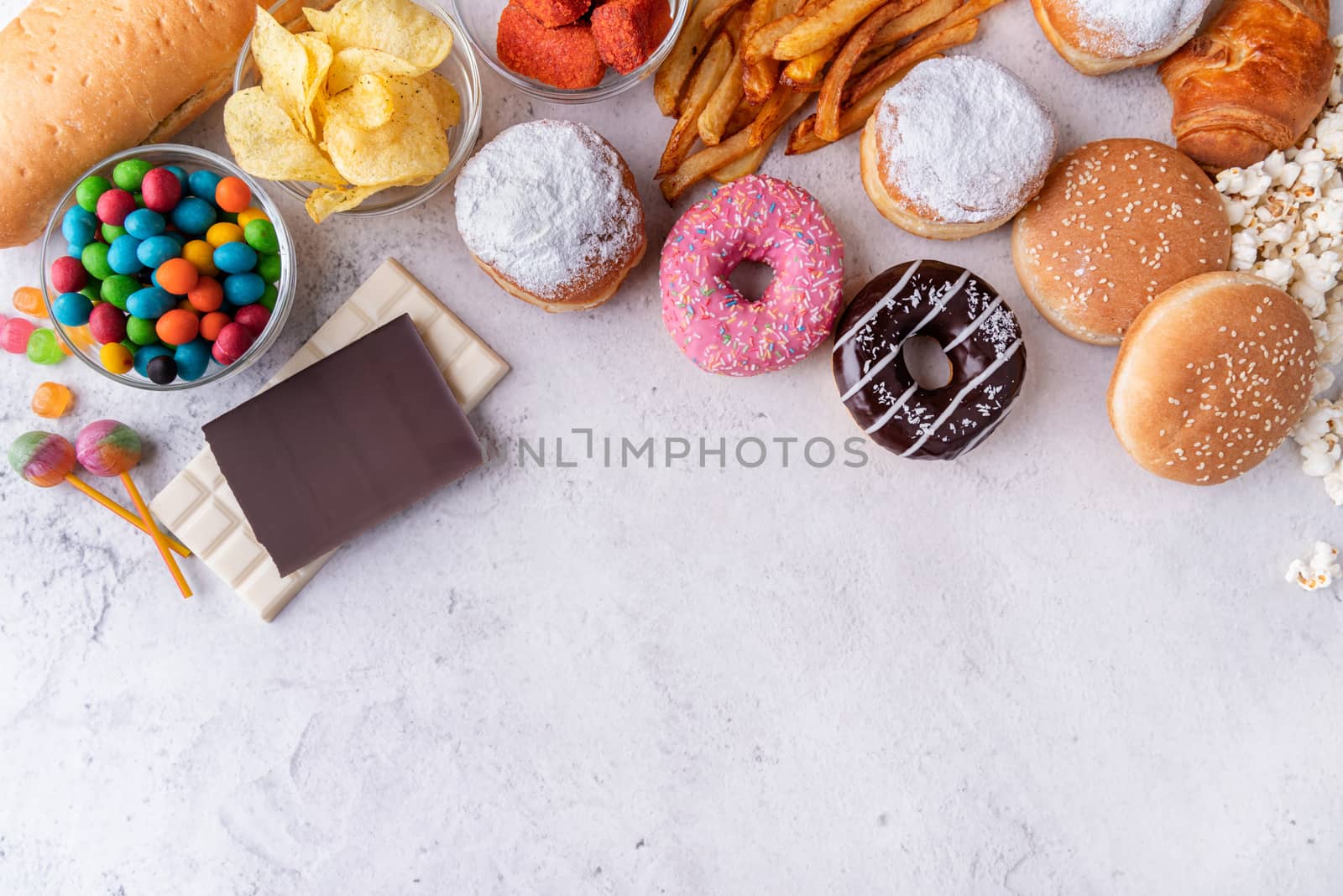 Unhealthy food and fast food with donuts, chocolate, burgers and sweets top view with copy space by Desperada