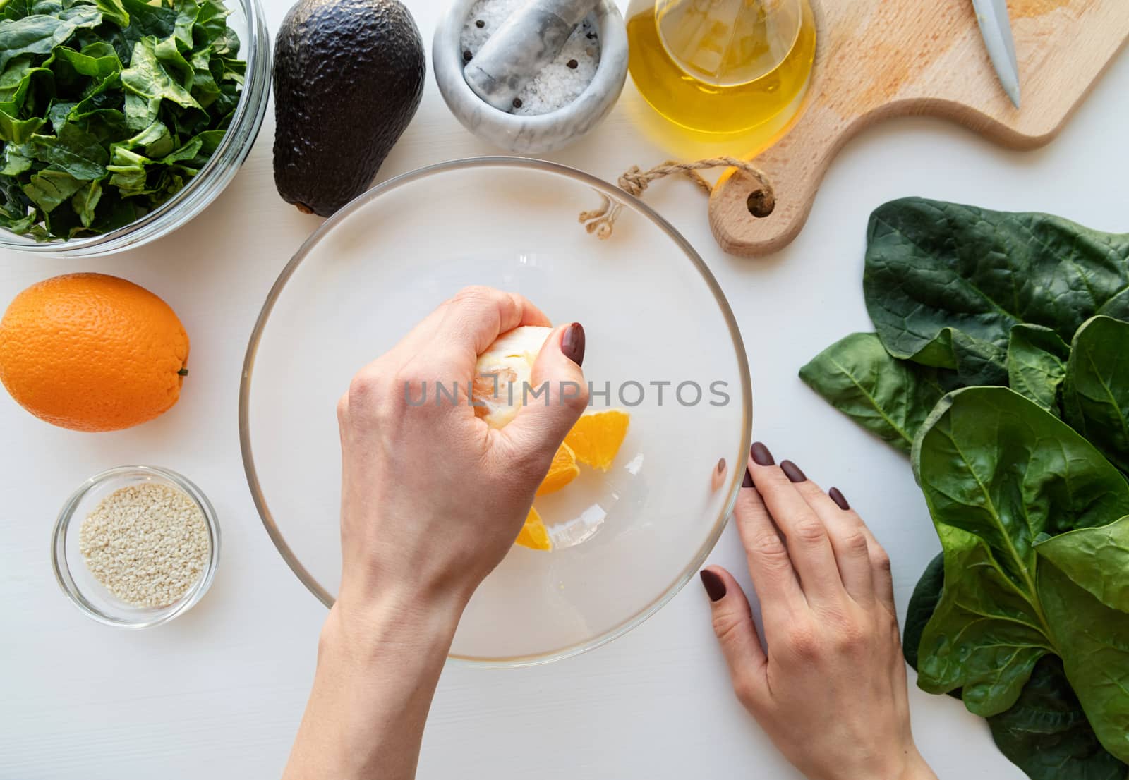 Step by step preparation of spinach, avocado and orange salad. Step 2 - squeezing the orange for the sauce, top view, selective focus