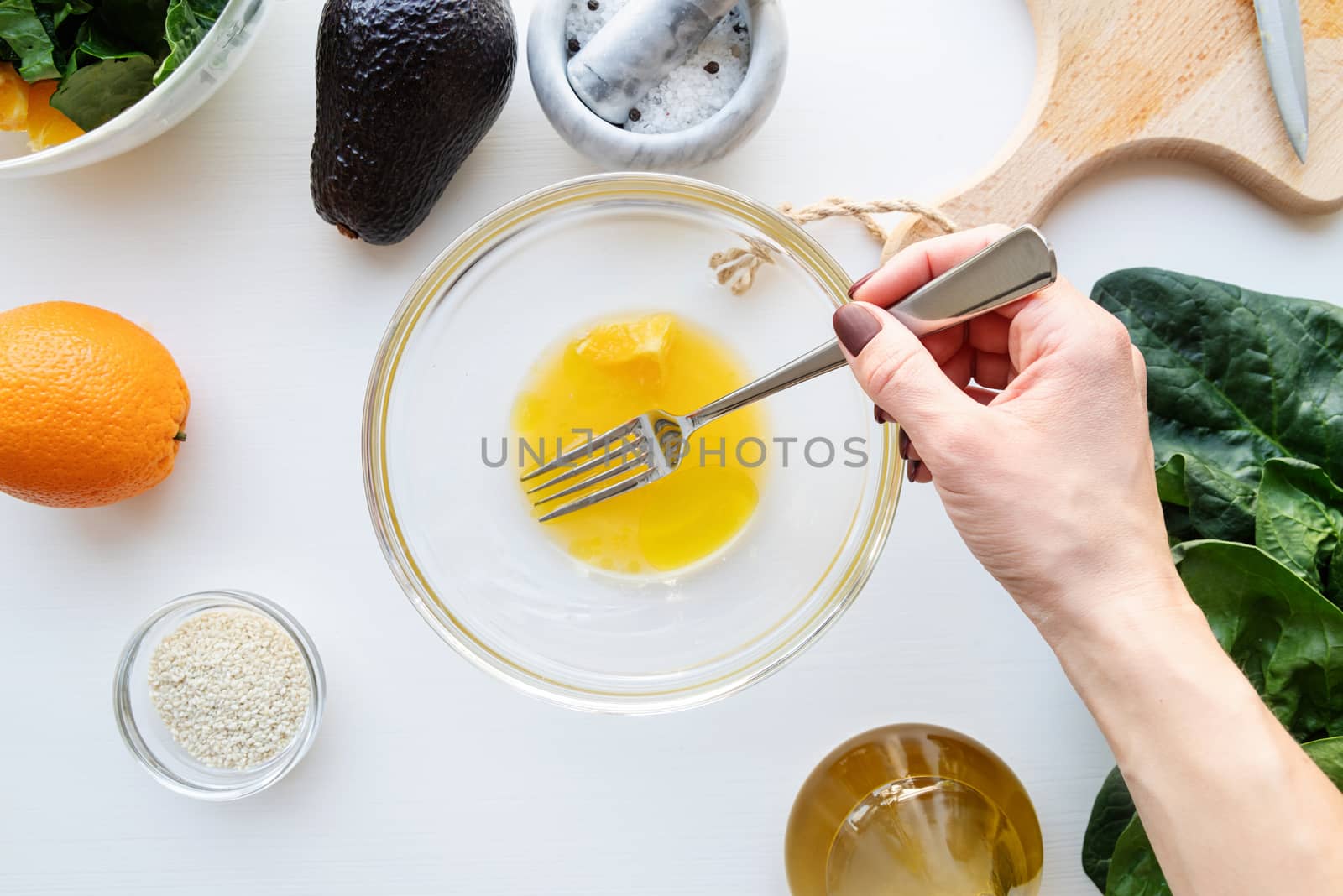 Step by step preparation of spinach, avocado and orange salad. Step 3 - mixing the orange juice and olive oil, top view, selective focus