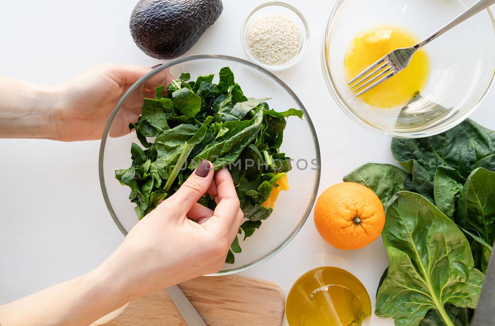 Step by step preparation of spinach, avocado and orange salad. Step 6 - putting together and mixing all ingredients, top view, selective focus