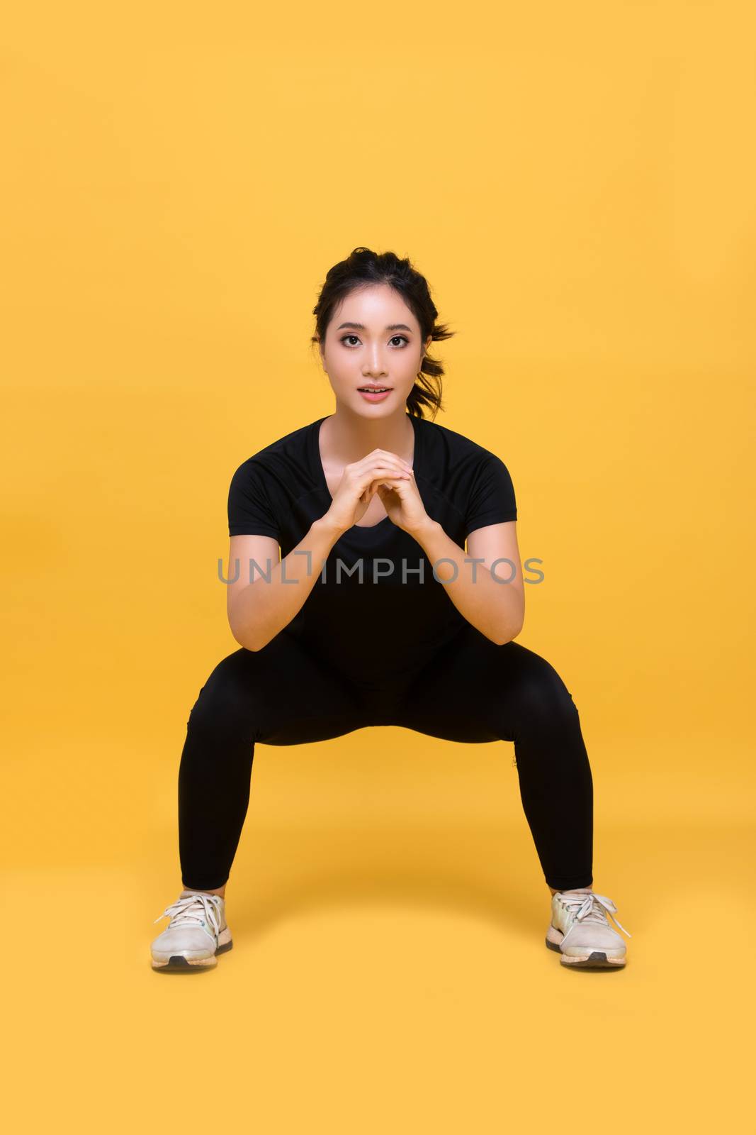 Smile happy Beautiful portrait young Asian woman stretching exercise workout on yellow background, fitness sport girl aerobic and healthy concept.