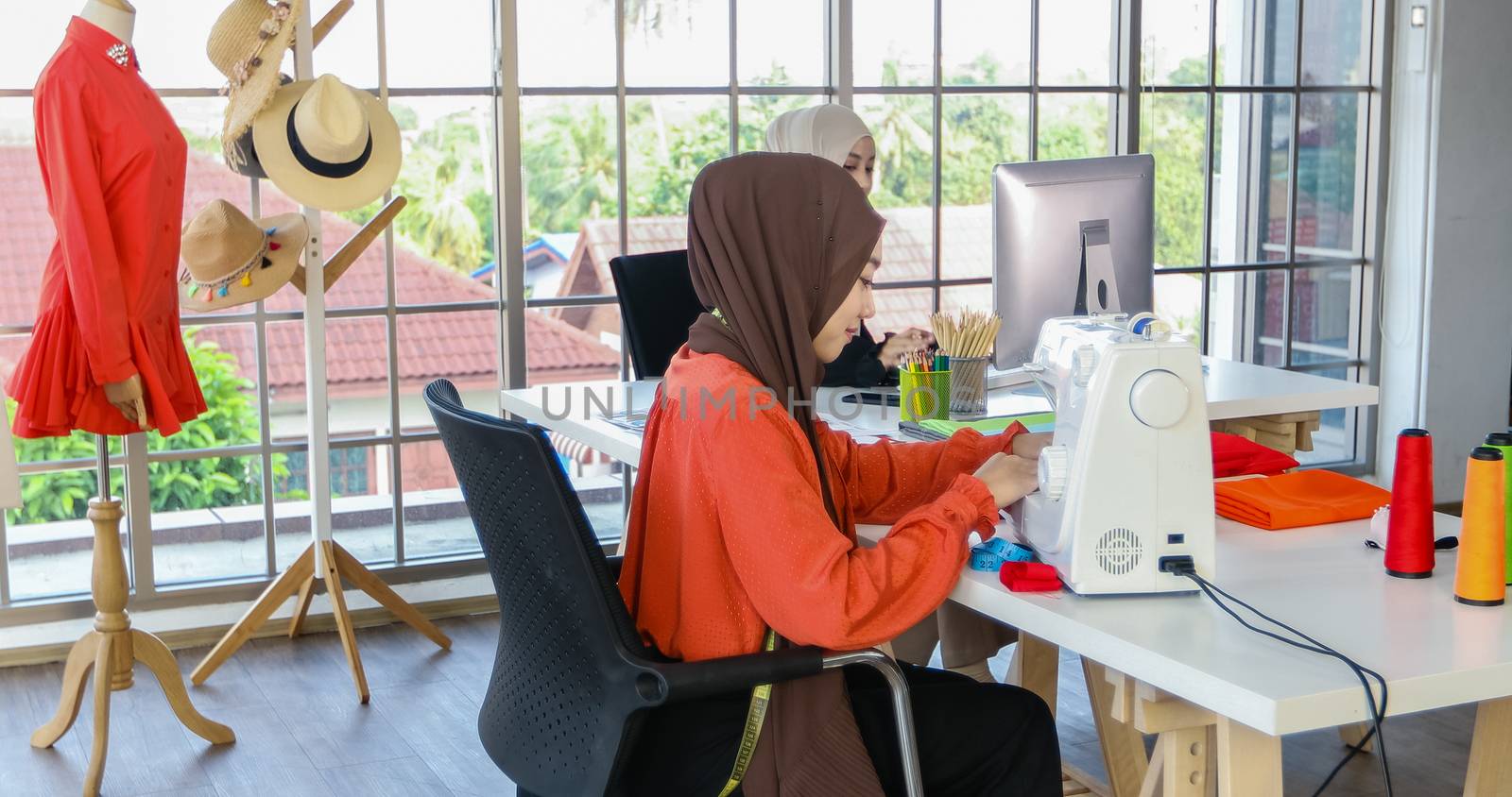 Small business of Muslim woman fashion designer Working and  using smart phone and tablet With Dresses at clothing store