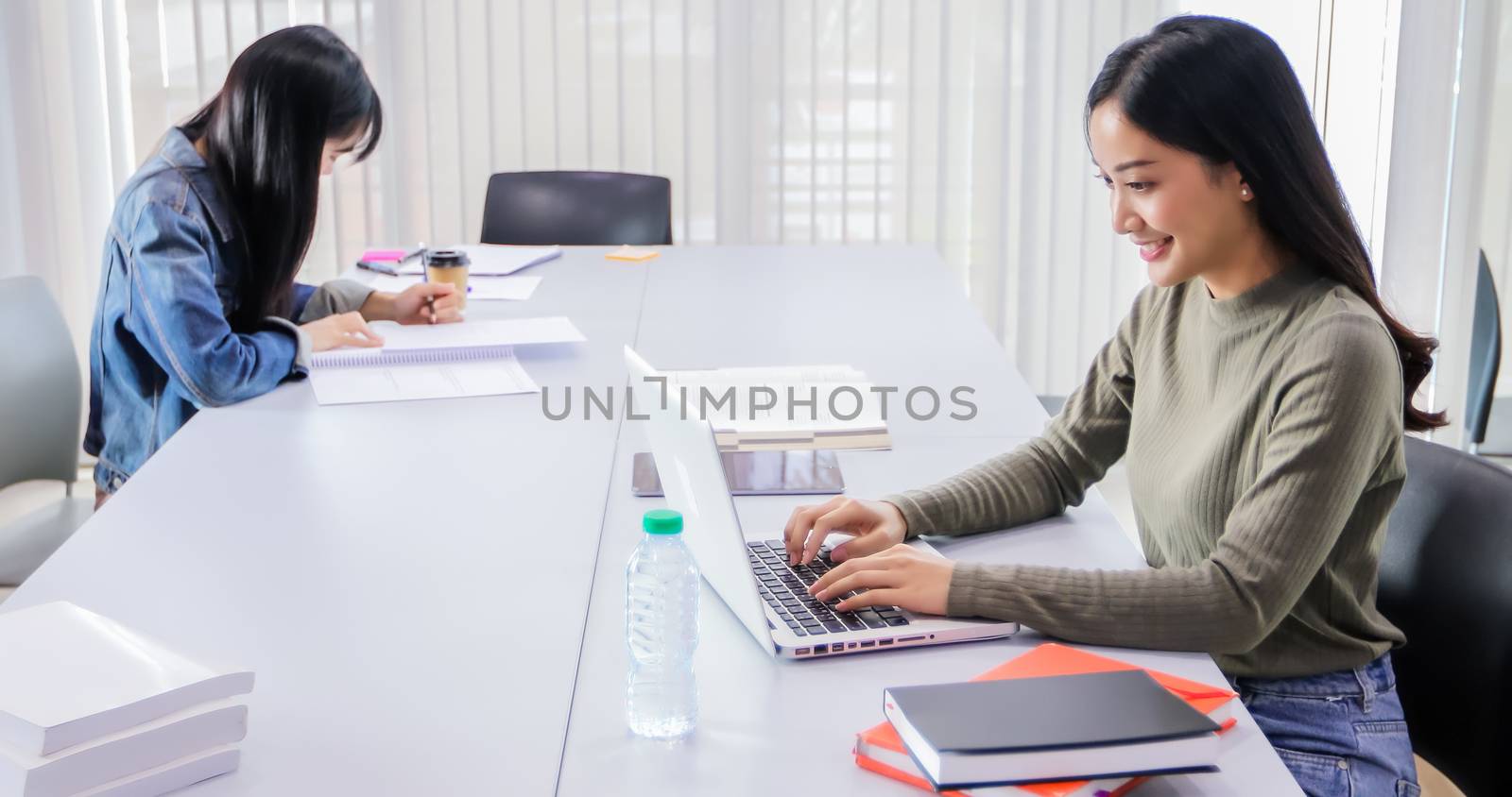 Asian women Students Smile and reading book and using notebook for working and sitting social distancing for infection risk