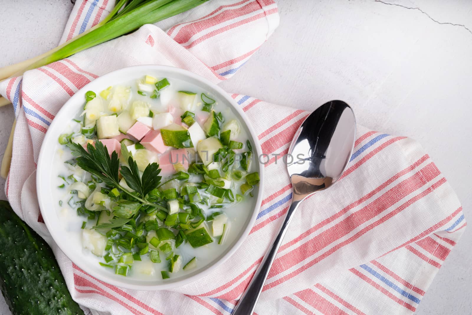 Okroshka. Traditional cold russian soup soup with sausage, cucumber, and green onion, top view copy space