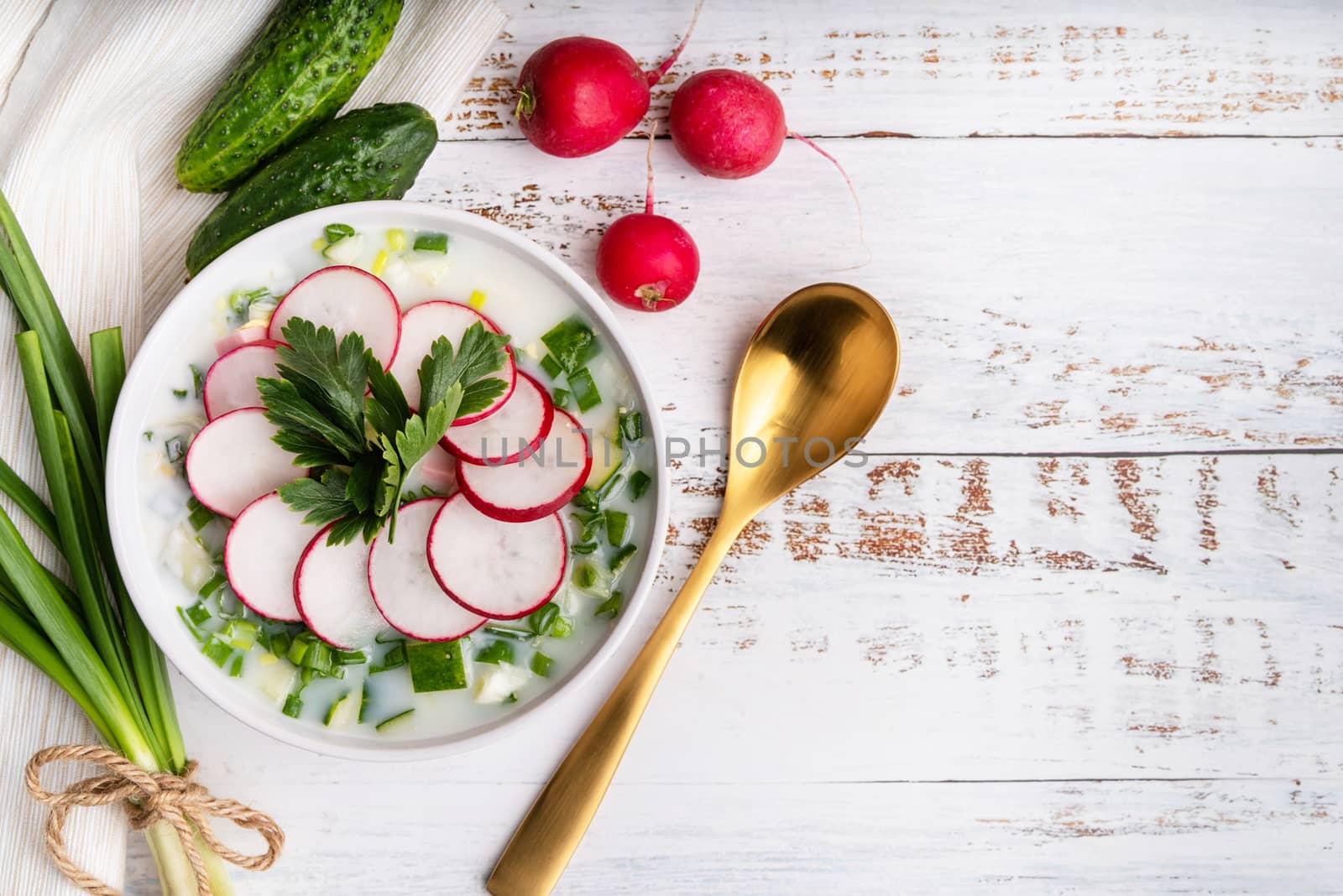 Okroshka. Traditional cold russian soup soup with raddish, sausage, , cucumber, and green onion, top view copy space