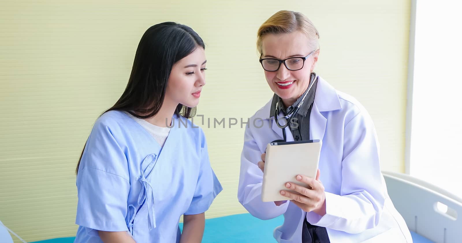 Doctor using digital tablet for explaining medication to woman patient in his office at Hospitals