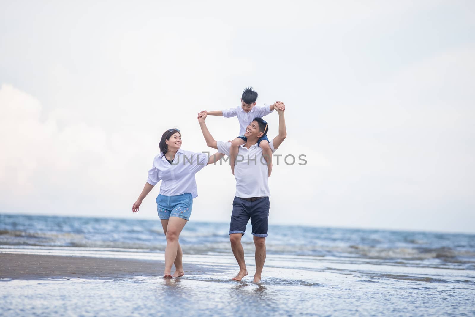 Active parents and people outdoor activity on summer vacations and holiday with children.Happy family and son walk with fun of sunset sea on sand beach.