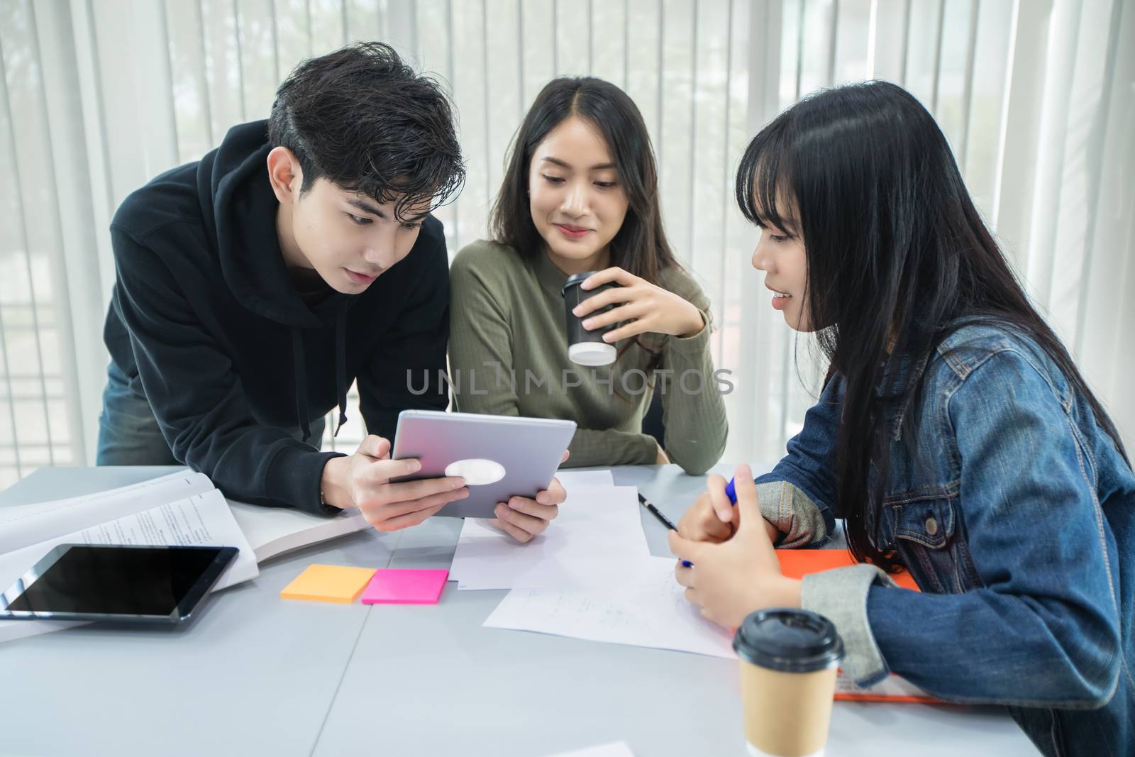 Asian students read books and use digital tablets to find information for work and online studies