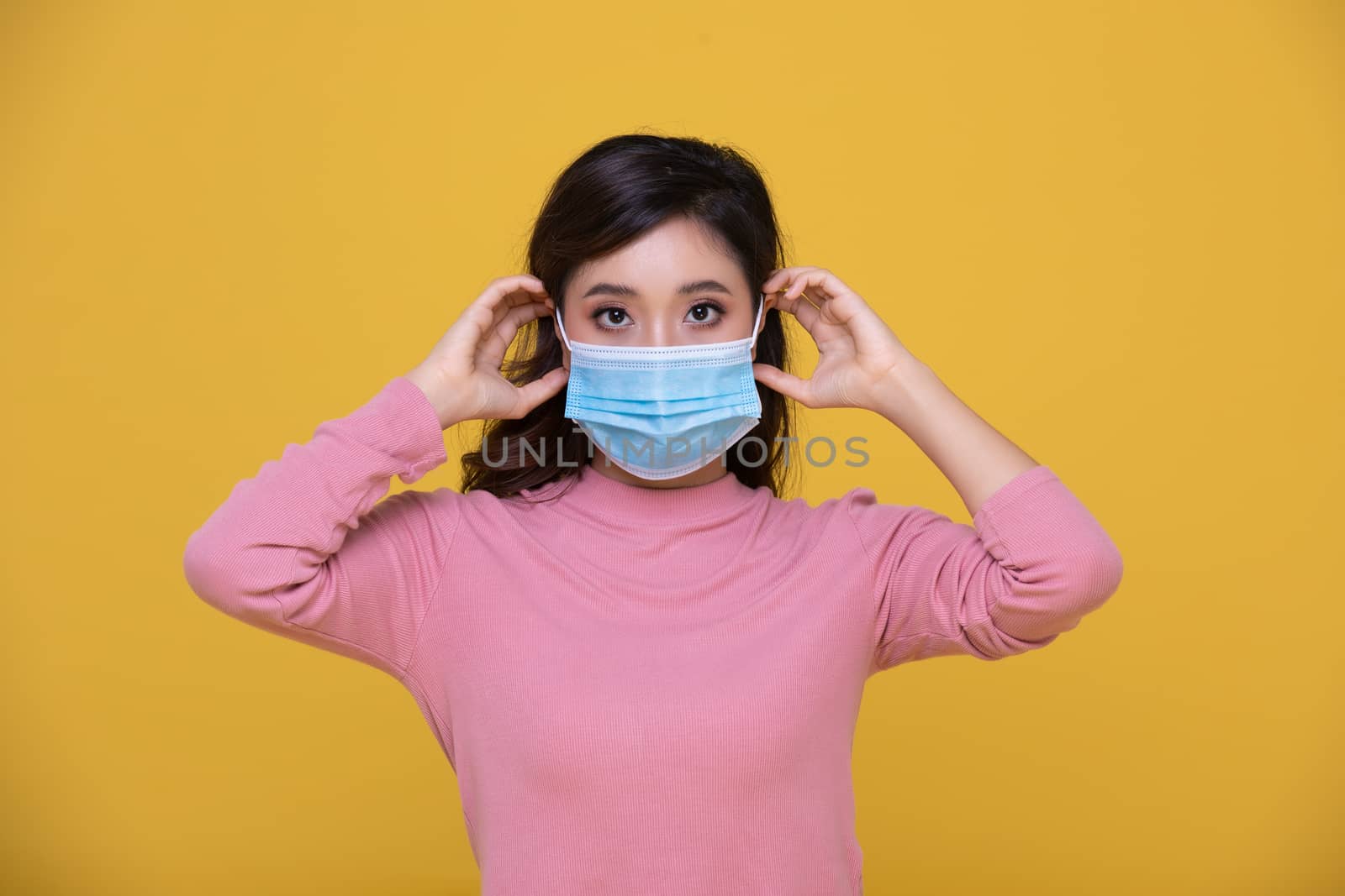 Portrait Asian beautiful happy young woman wearing  face mask or protective mask against coronavirus crisis or COVID-19 outbreak on yellow background