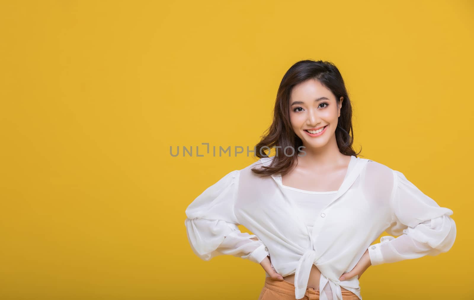 Portrait Asian beautiful happy young woman smiling cheerful and looking at camera isolated on yellow studio background