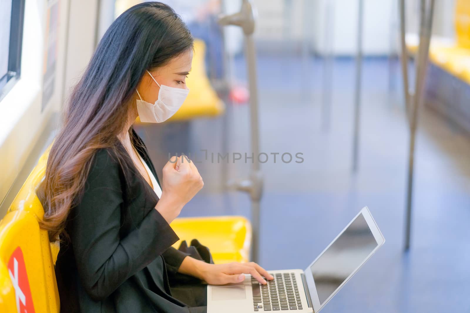 Business girl with hygiene mask use laptop for working in the sky train by nrradmin