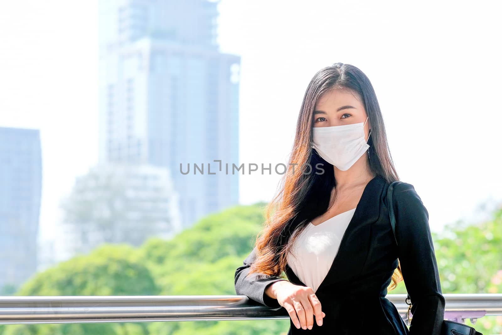 Beautiful woman with hygiene mask stand near the railings of sky train platform by nrradmin