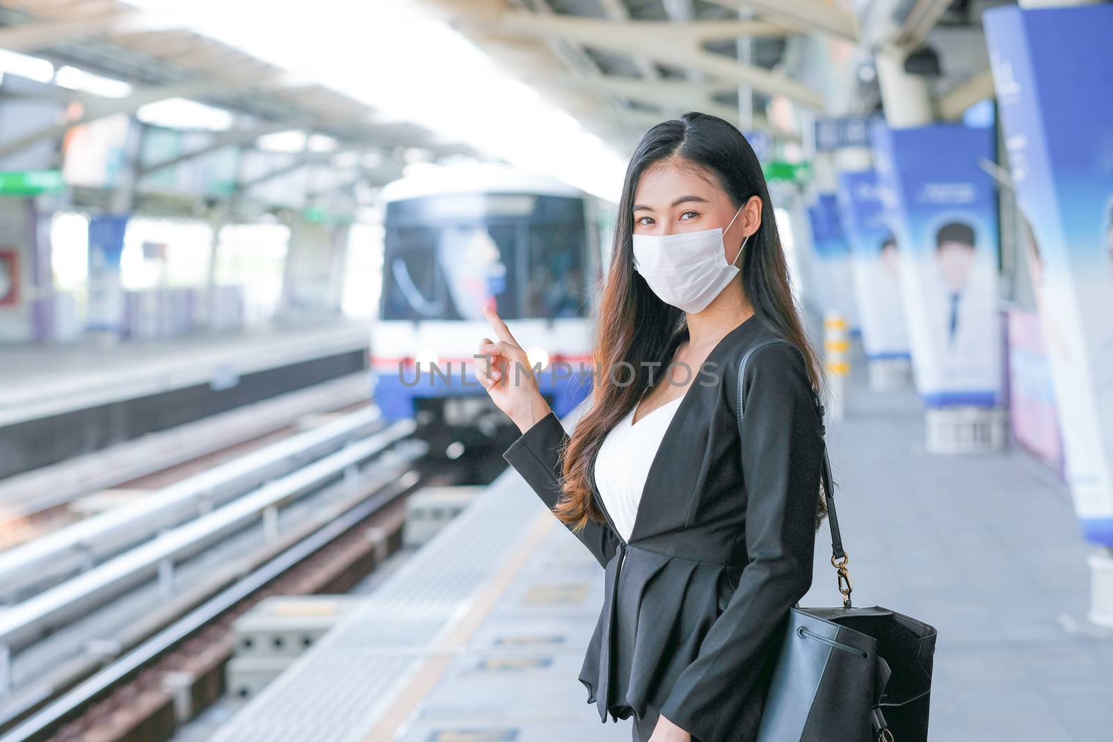 Beautiful business woman with hygiene mask stand in front of sky train by nrradmin