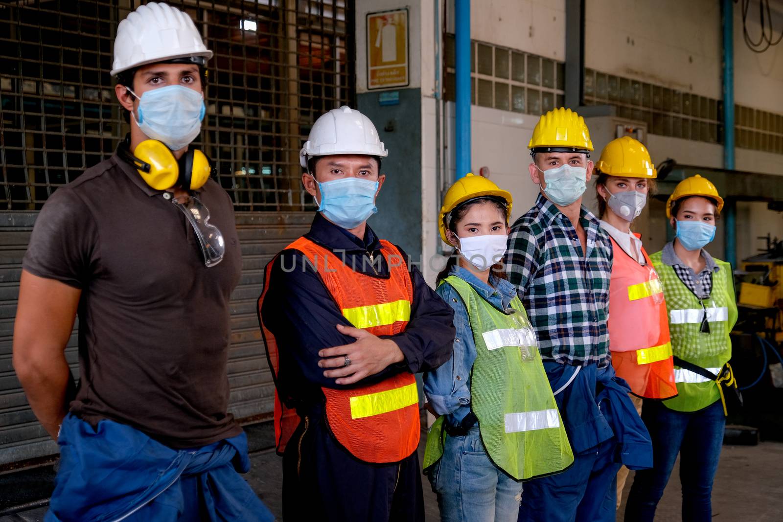 Group of workers or technician with mask stand and look right side direction and stay in factory area.