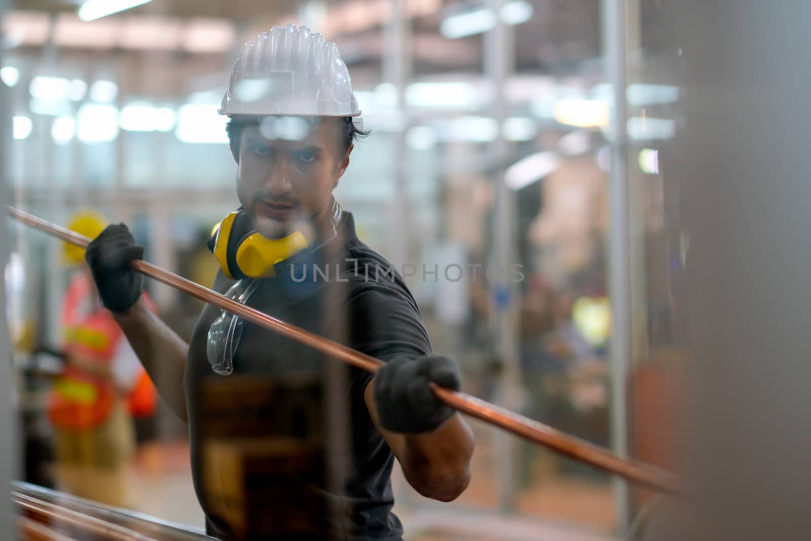 Technician or worker man hold copper pipe and look through glass window in the factory.