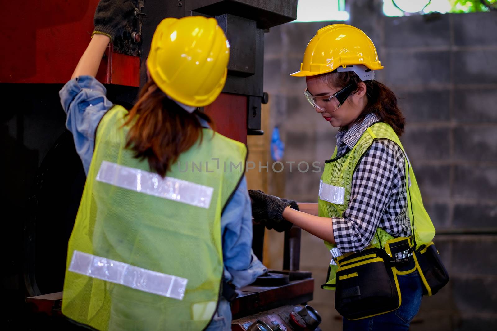 Pretty woman workers or technician are working with machine in factory.