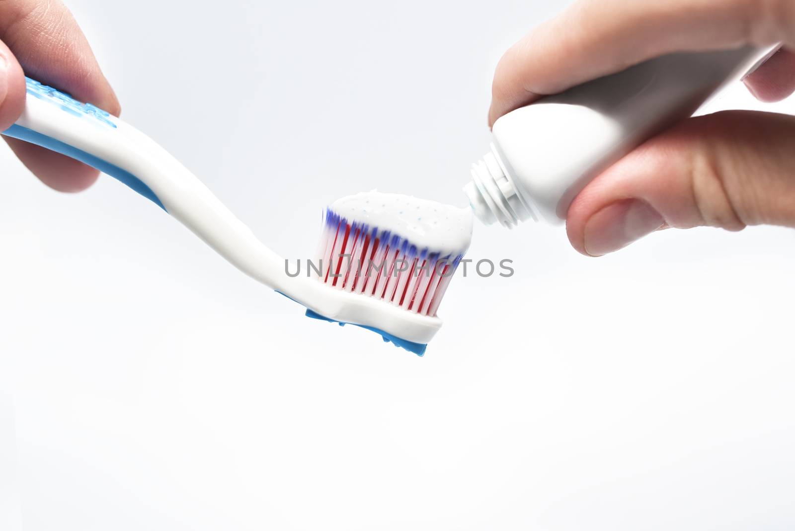 Fresh toothpaste and toothbrush in the male hands, isolated on white background
