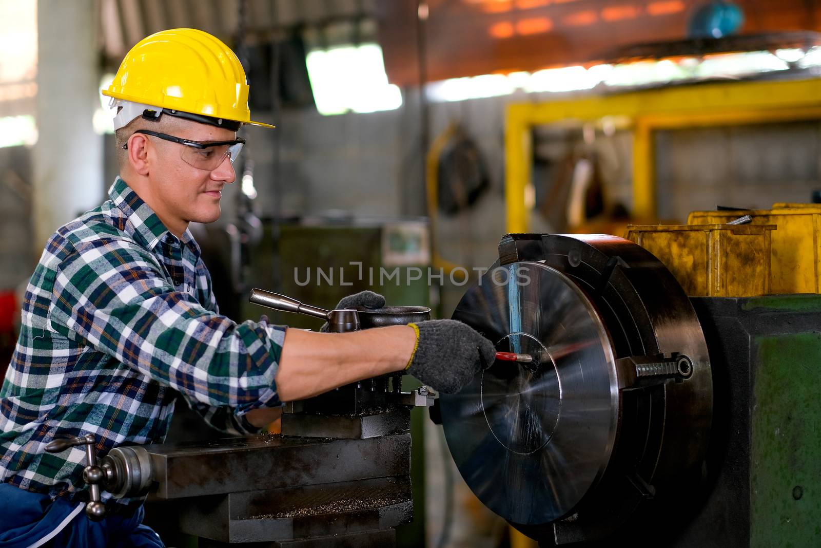 Side view of smart technician or engineer worker with protective uniform maintenance machine in factory workplace. Concept of good system of management get better industrial business.