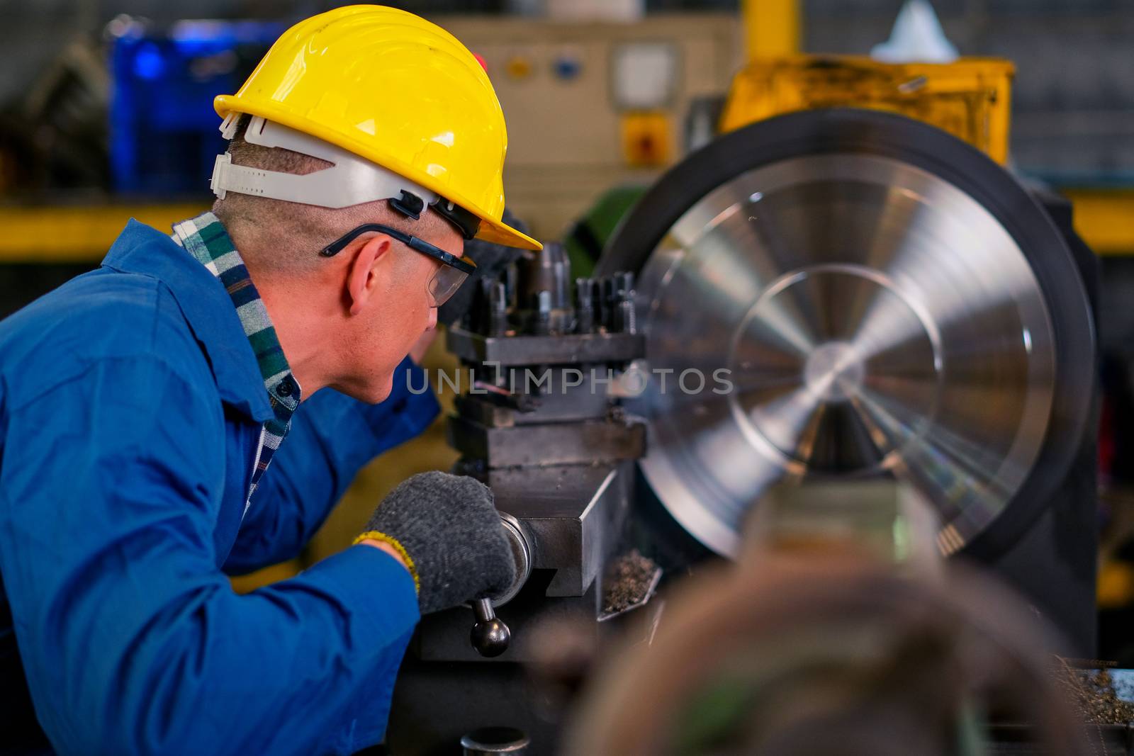 Side back of smart technician or engineer worker man with protective uniform look to the machine working in factory workplace. Concept of good system of management to get better industrial business.