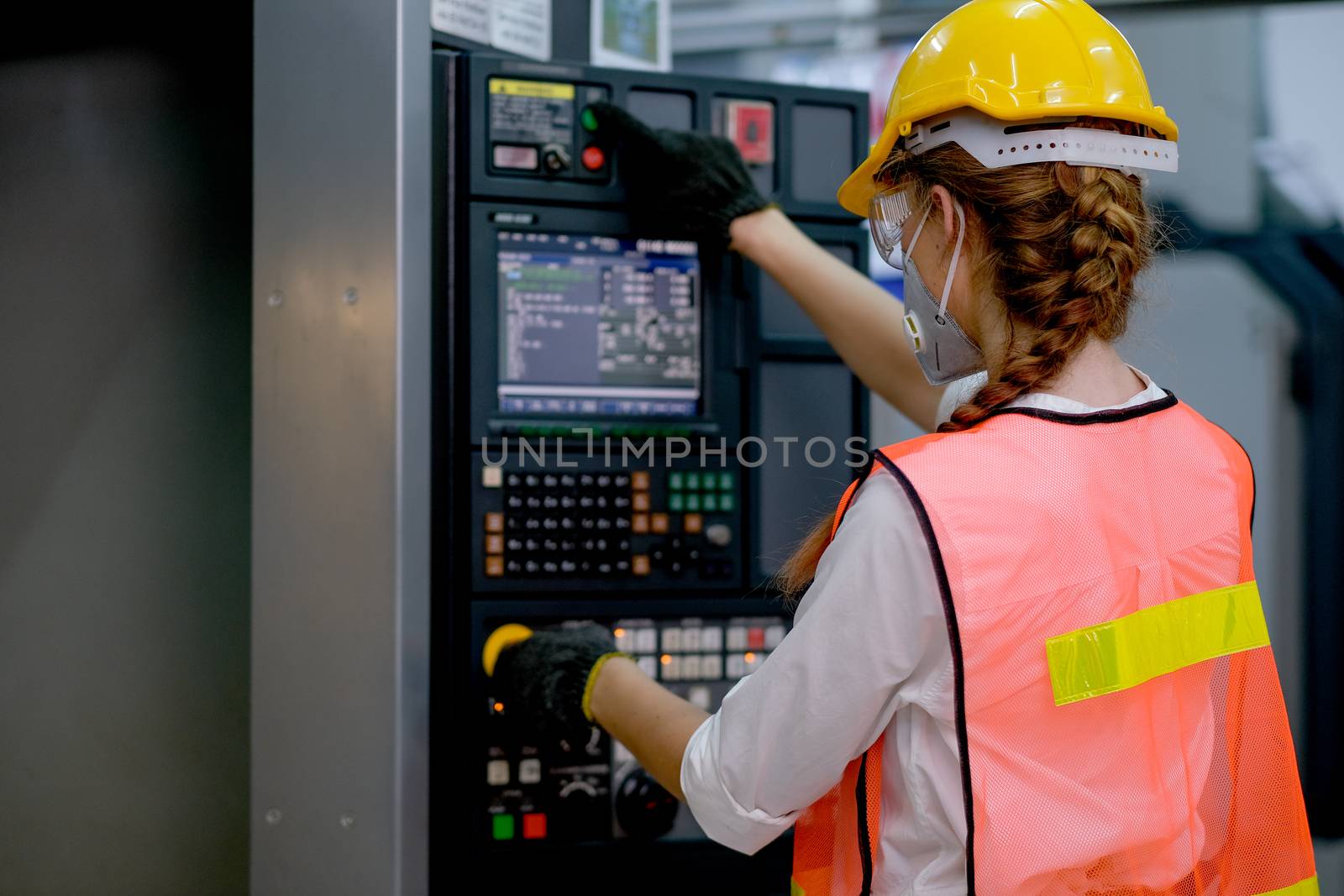 Beautiful factory woman with mask work with machine by monitoring and control function button.