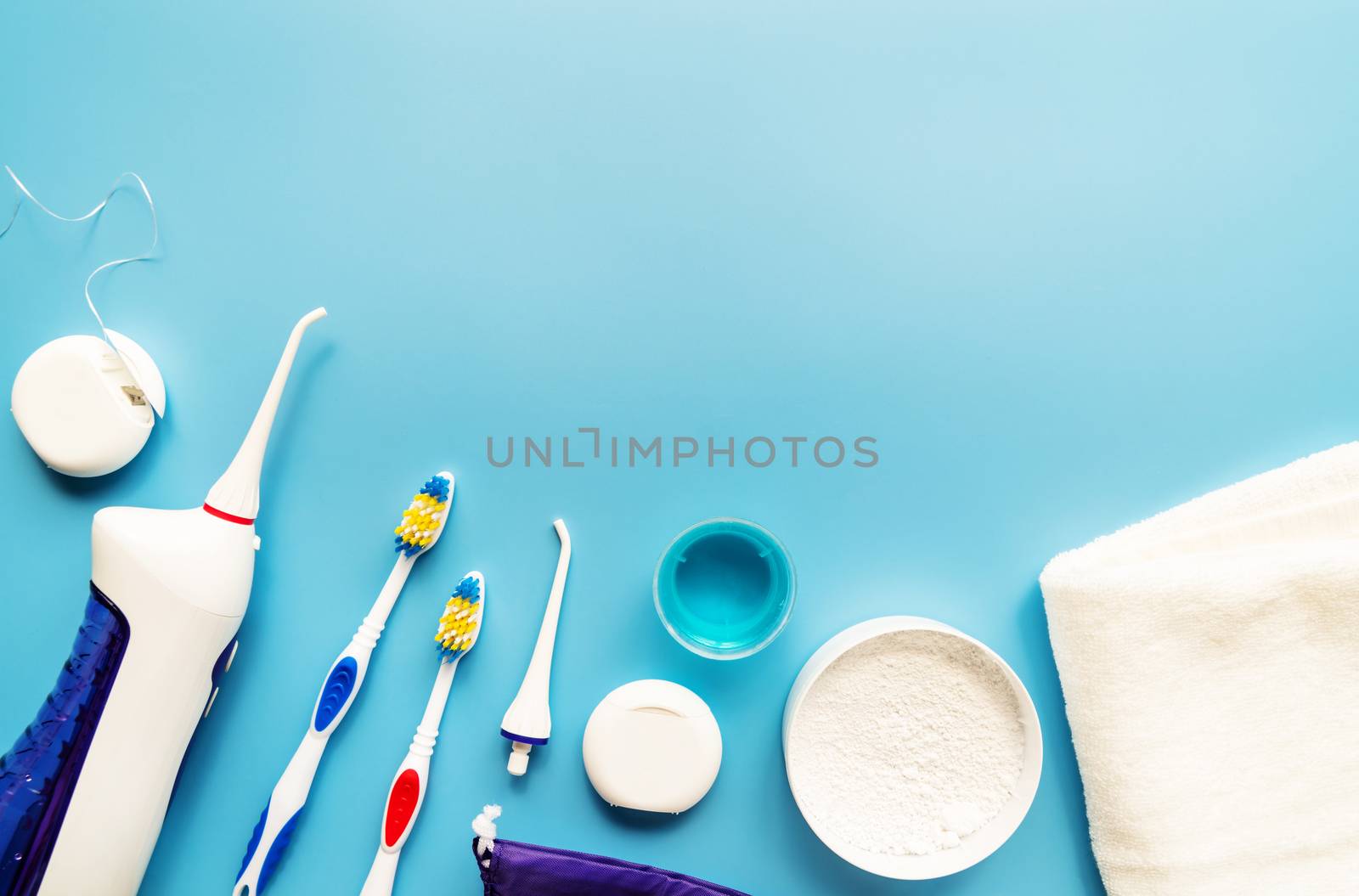 Dental tools, floss, mouth irrigator, toothbrushes and tooth powder top view on blue background by Desperada