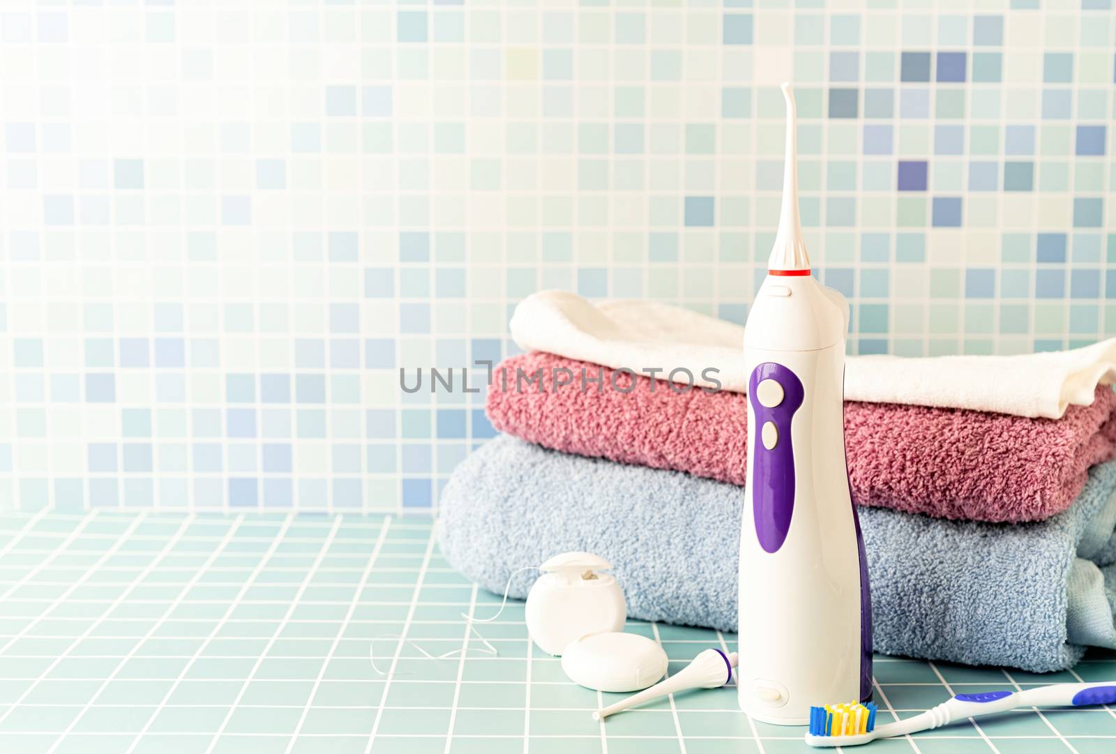 Electronic tooth irrigator, toothbrushes and a pile of towels front view copy space by Desperada