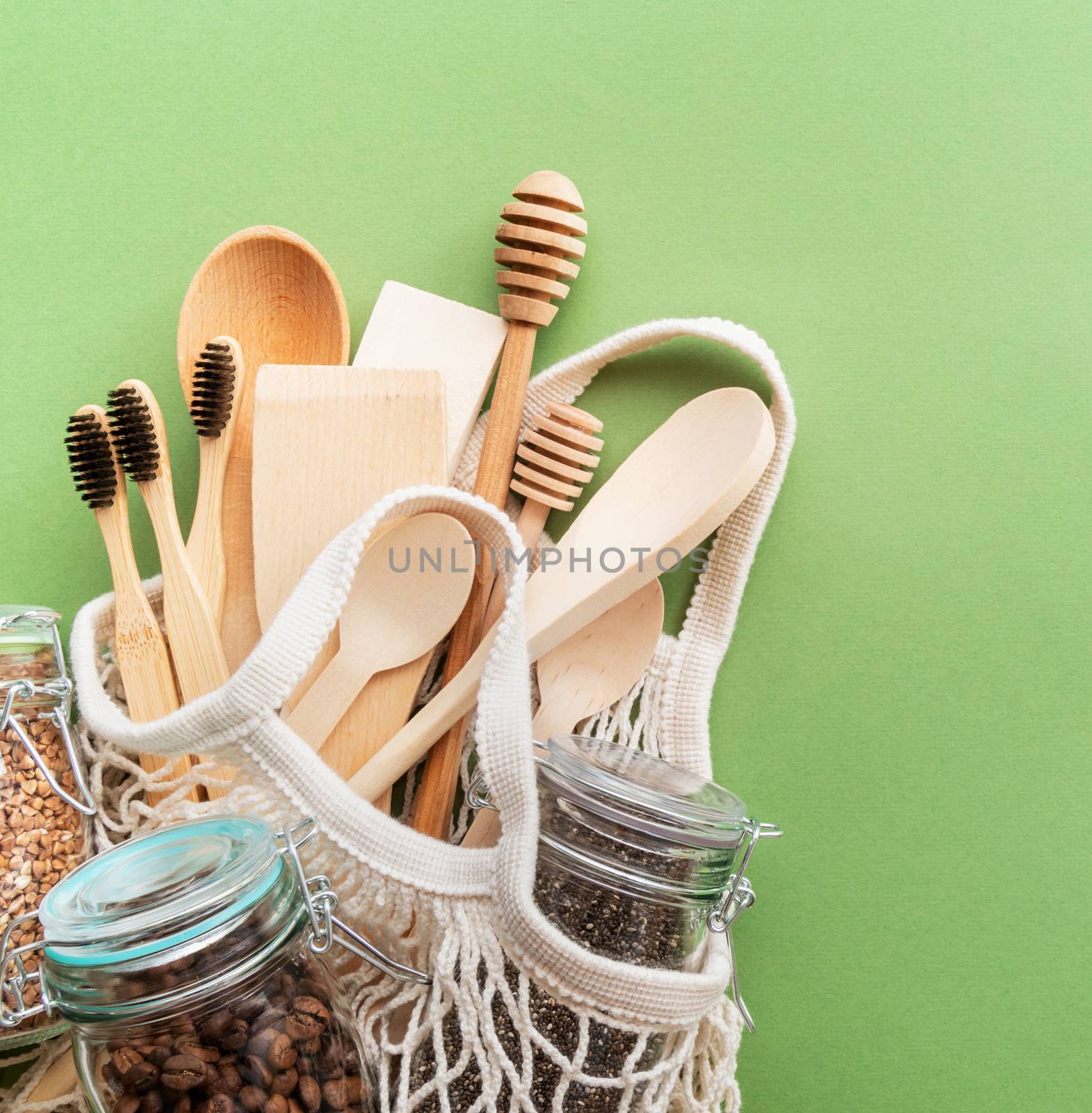 Zero waste eco friendly bag and wooden tools top view on green background with copy space