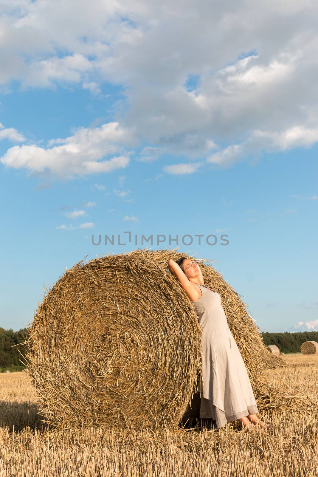Young girl and round straw bales