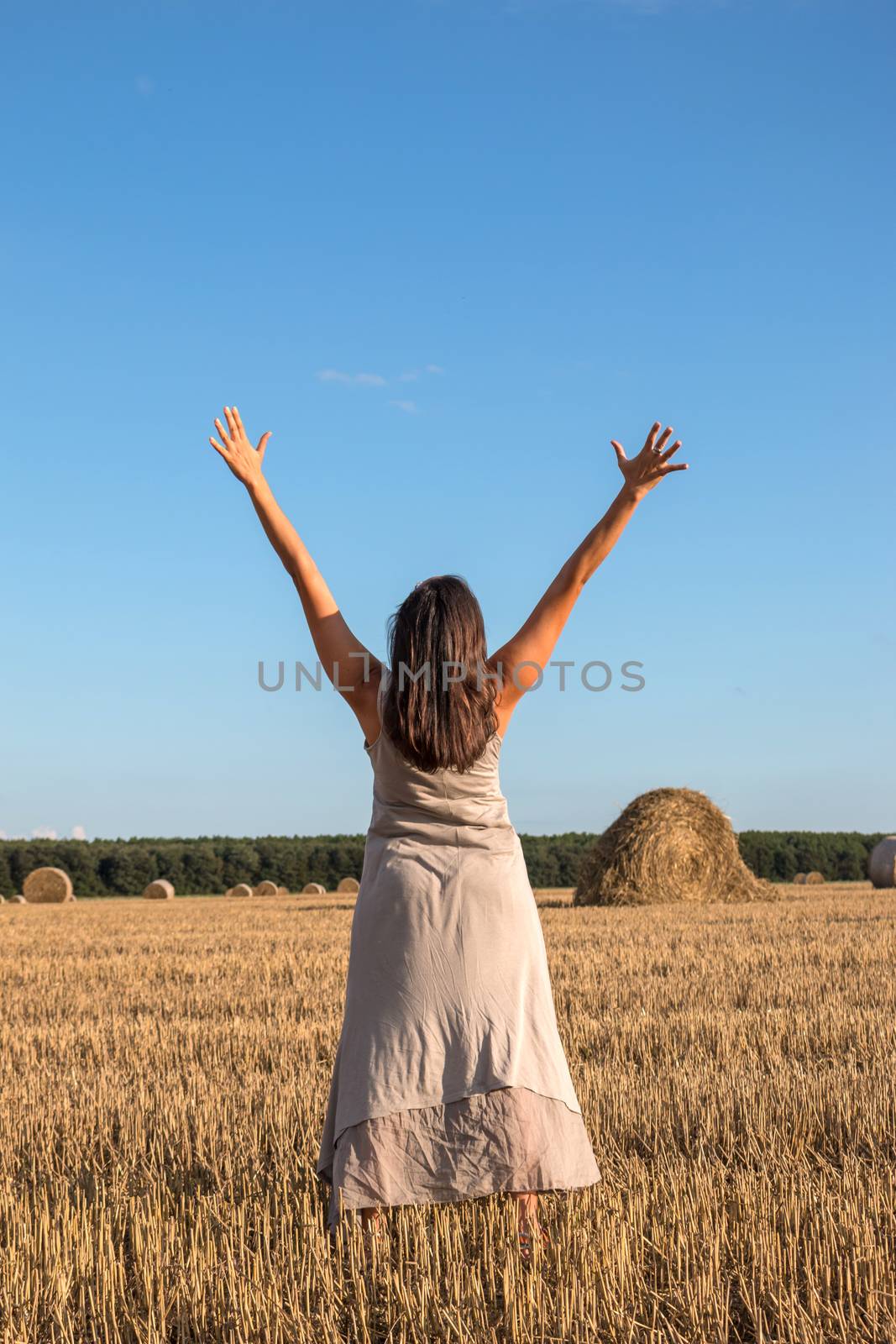 Young girl and round straw bales