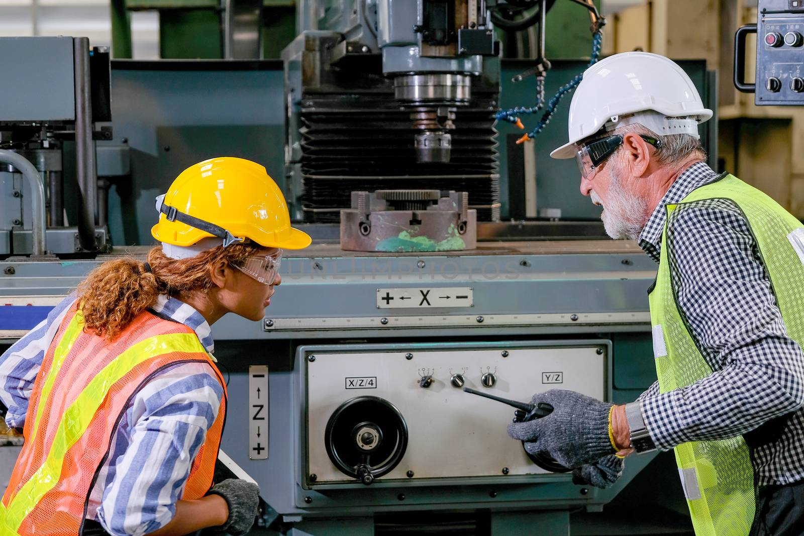 Old and young technicians check the problem of machine in factory. by nrradmin