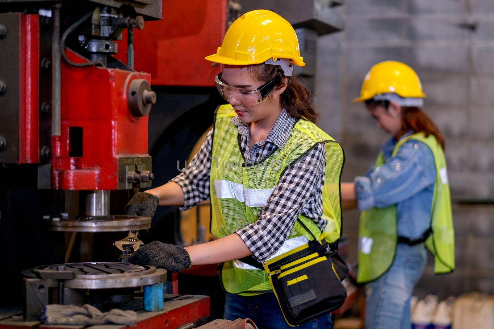 Pretty woman engineer workers or technicians with safety uniform are working with machine in factory by nrradmin