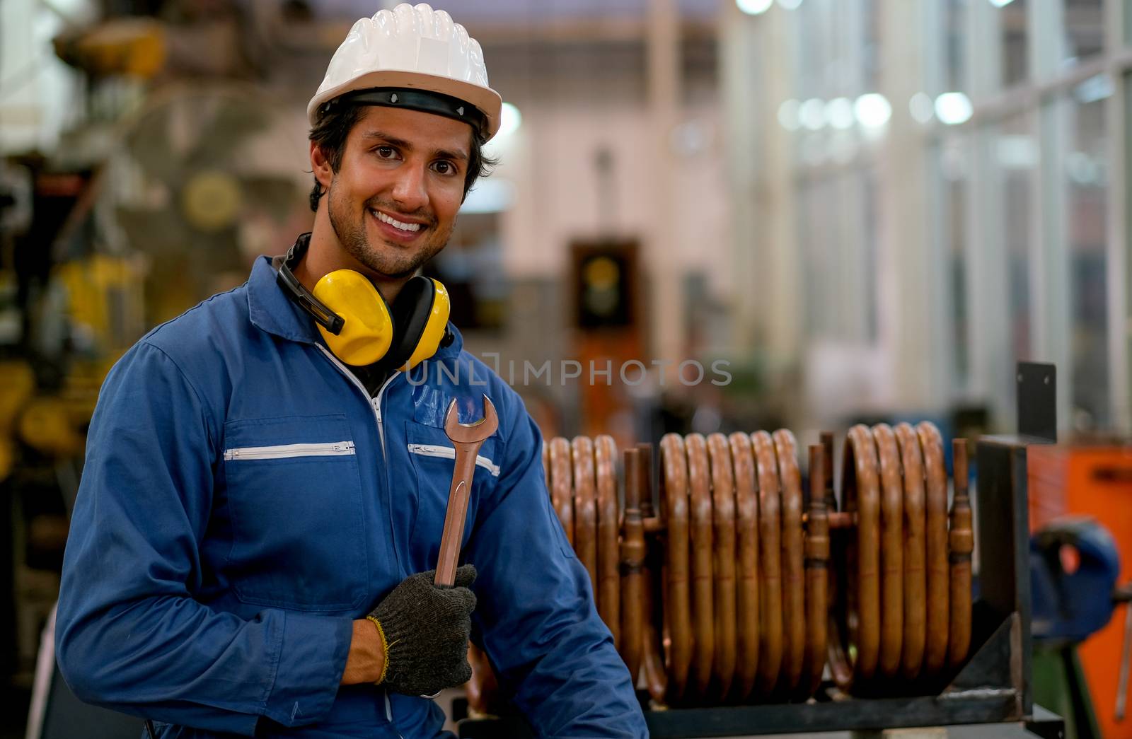 Portrait of worker or technician man hold wrench, smile and stand in front of copper pipe in factory. Concept of good system and manager support for better industrial business.