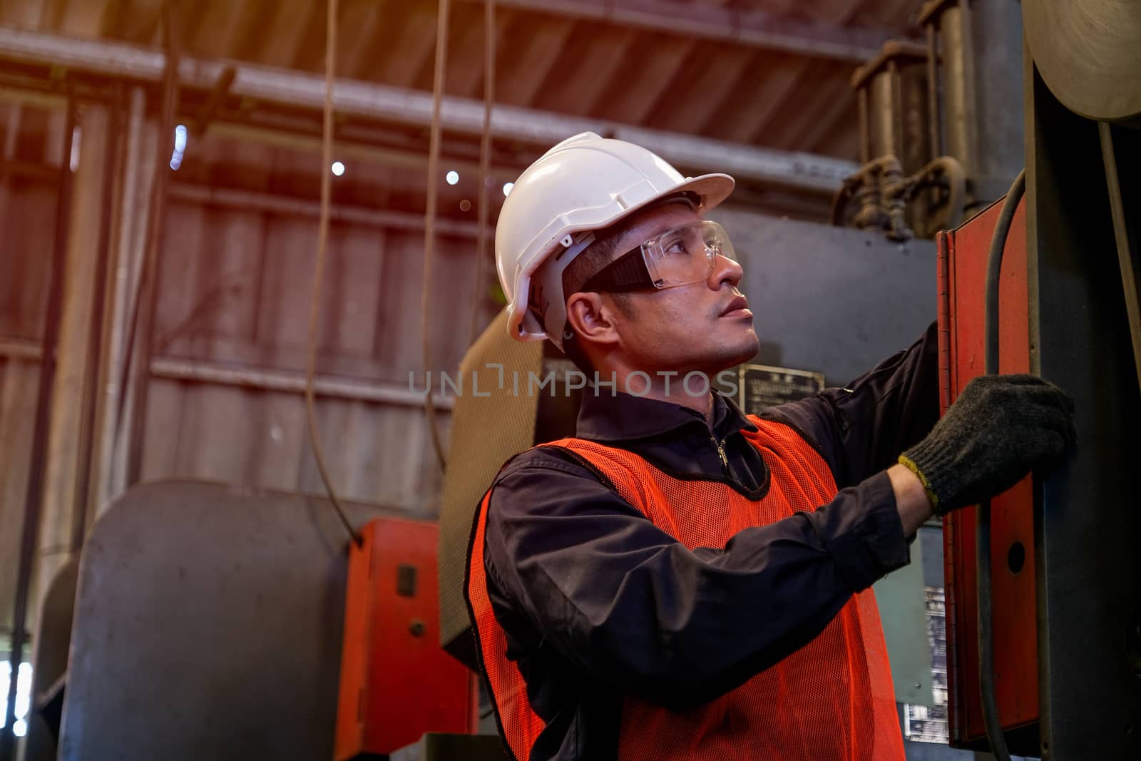 Portrait of asian engineer worker or technician works with machine in factory workplace. Concept of good system and manager support for better industrial business.