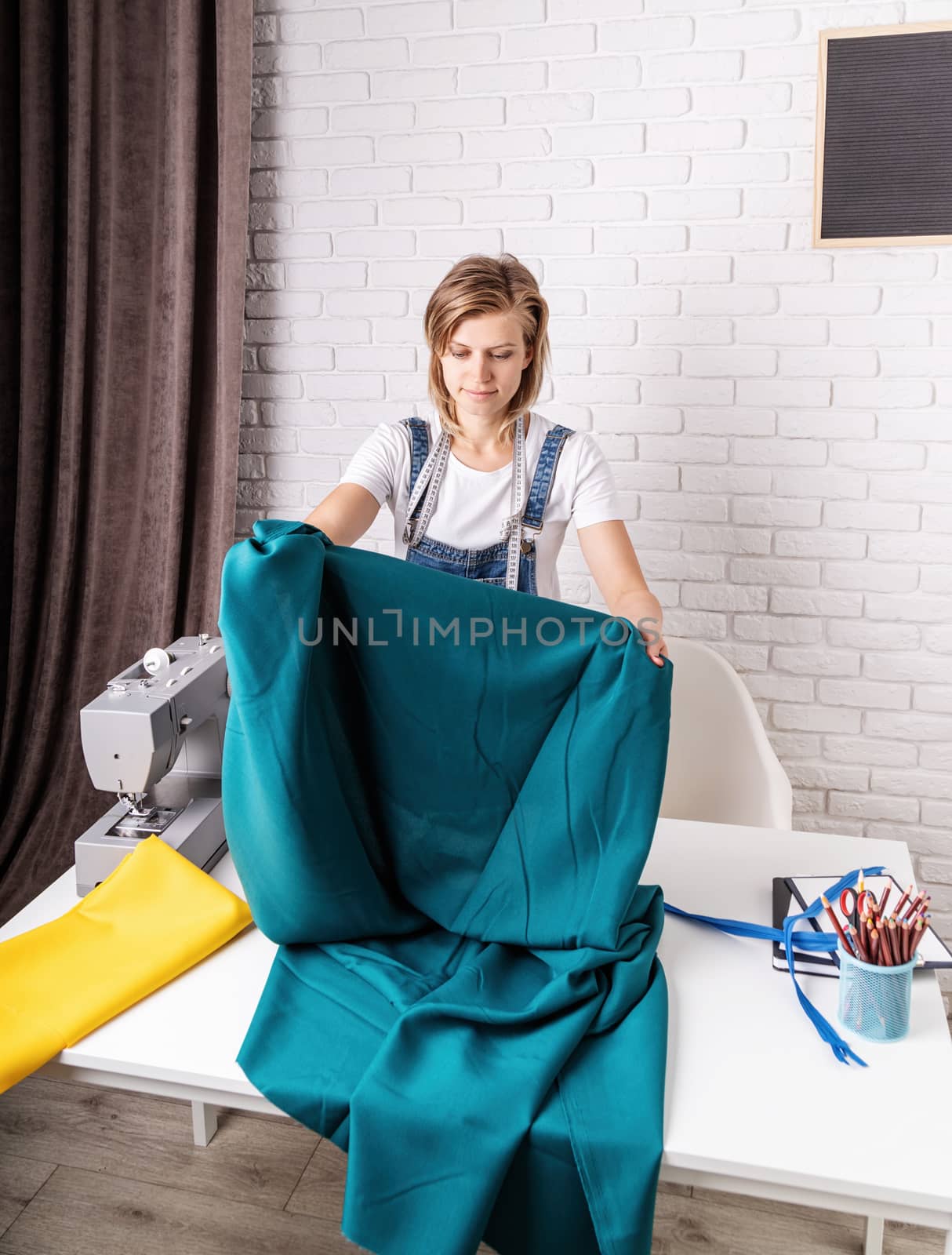 Woman tailor working with textile in her studio by Desperada