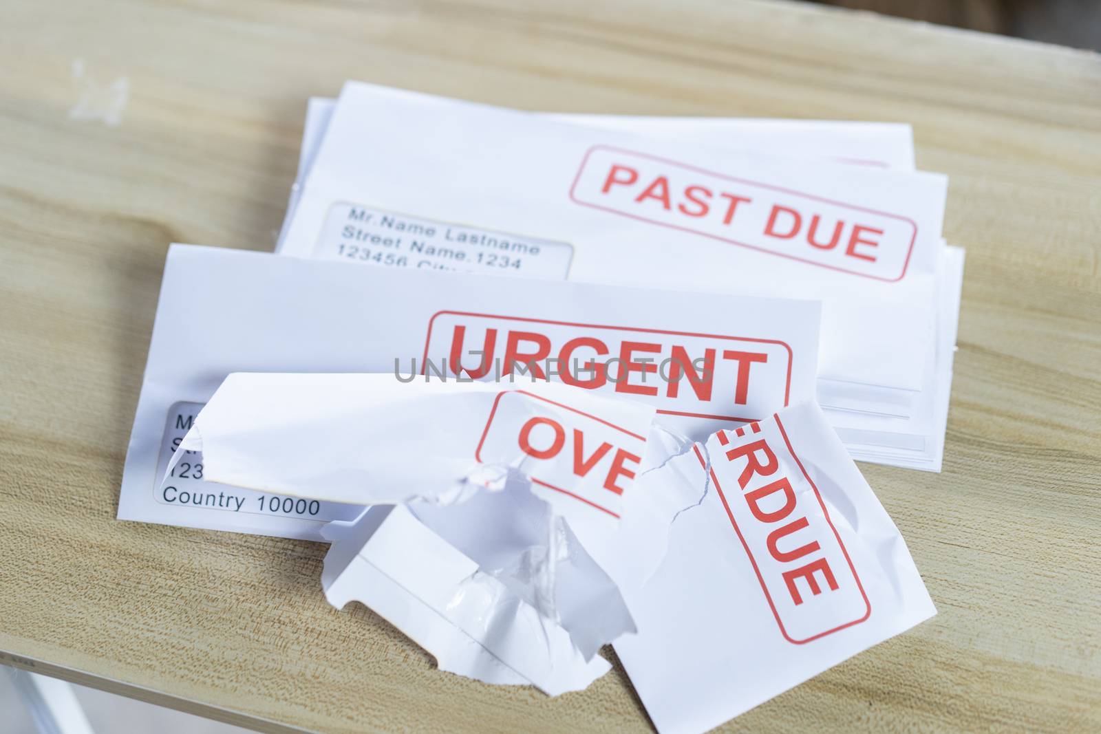 Debt letters that are collected on past overdue bills and final announcements on the table. Red writing to represent the struggle against economic unemployment.
