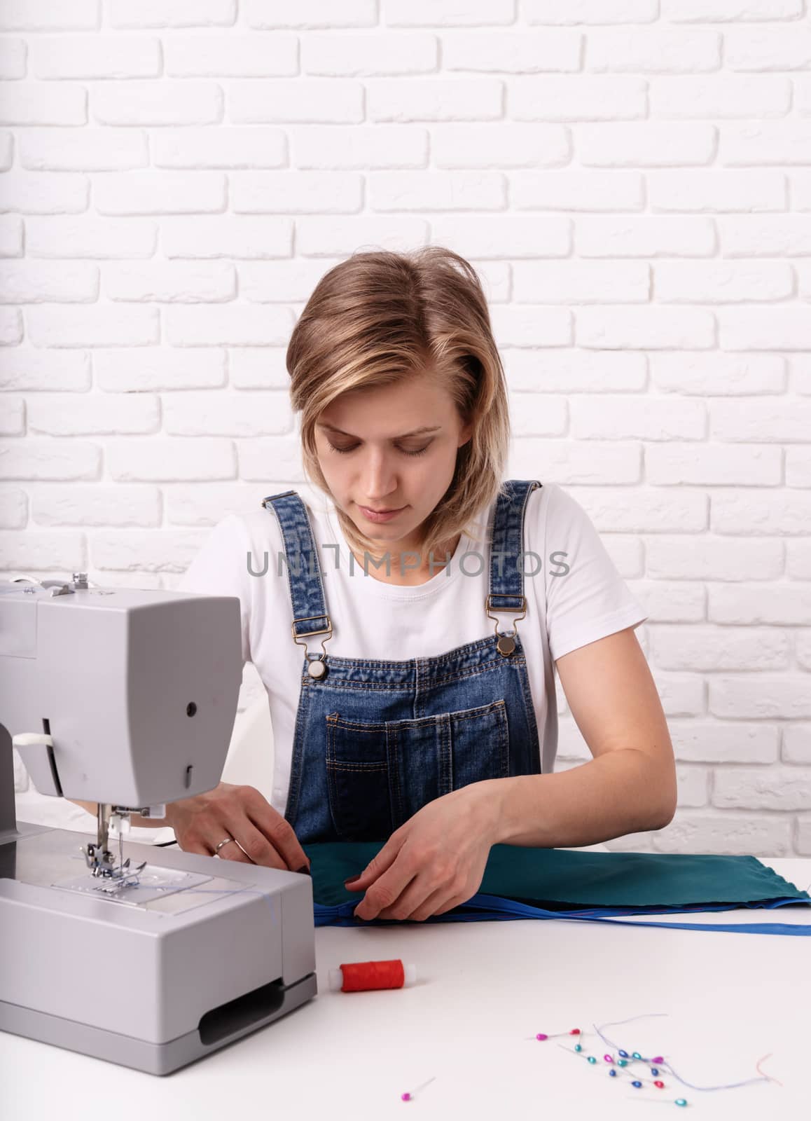 Woman tailor working with textile in her studio by Desperada