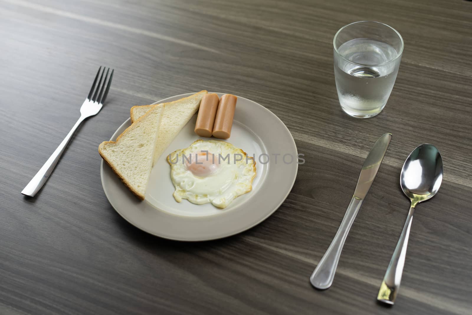 Breakfast on a white plate on the wooden floor.