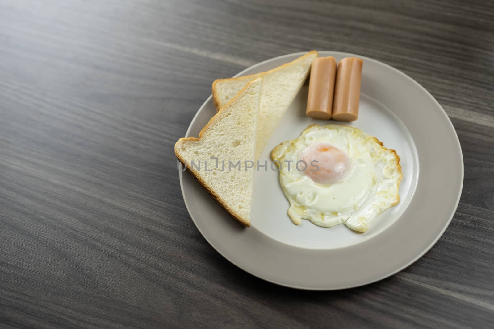 Breakfast on a white plate in the lower right corner on the wooden floor
