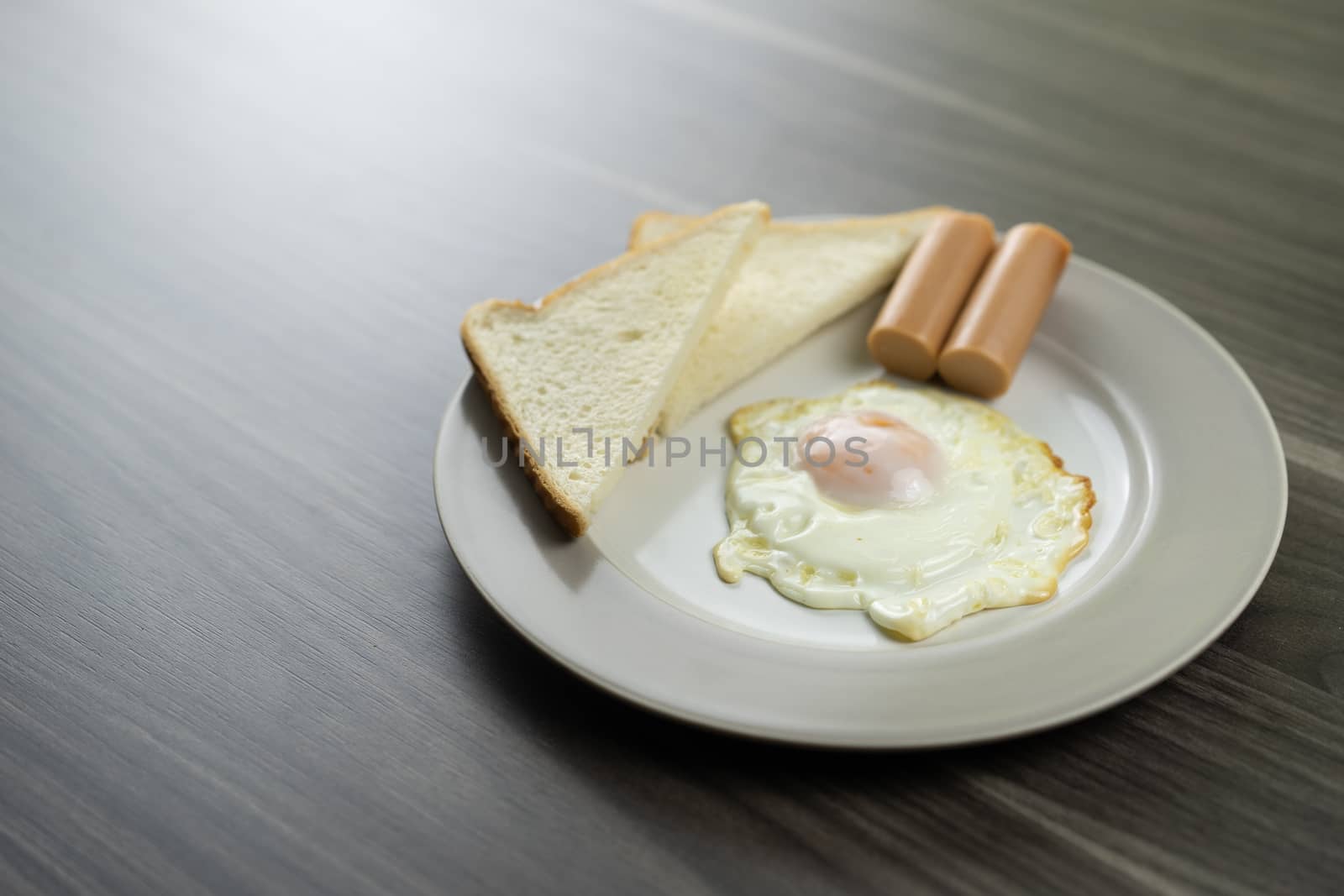 Breakfast on a white plate in the lower right corner on the wooden floor