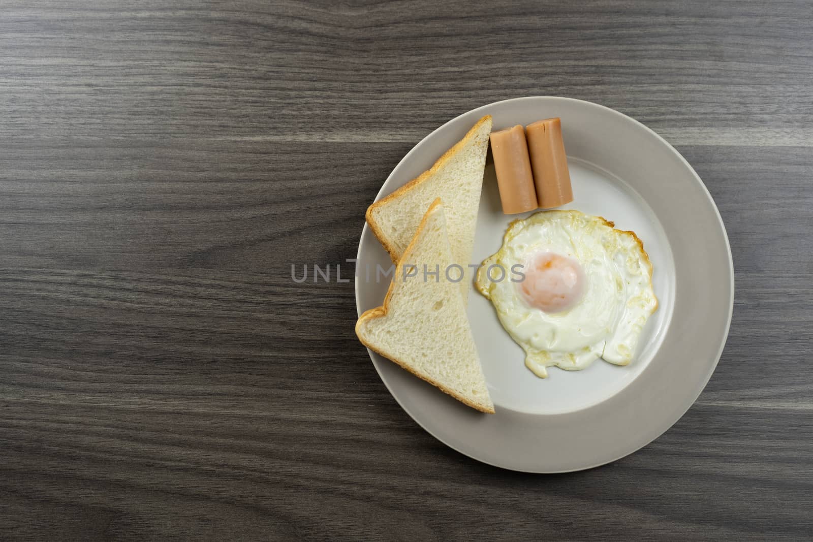 Breakfast on a white plate on the right corner of the wooden floor