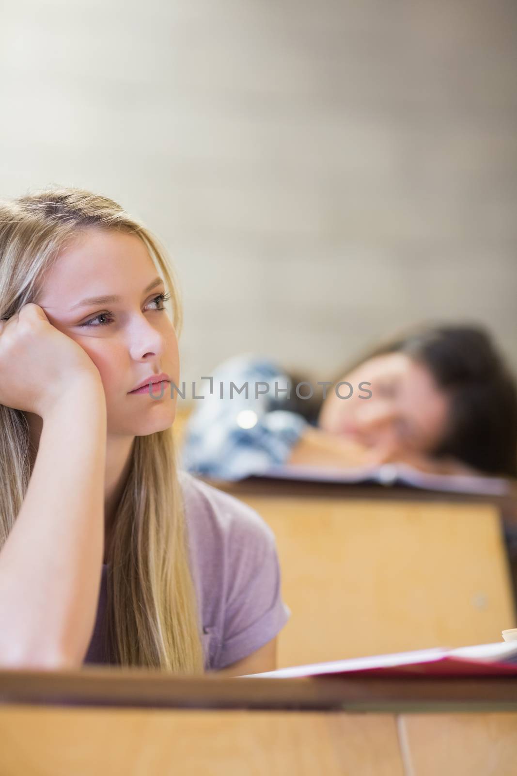 Bored student listening while classmate sleeping by Wavebreakmedia