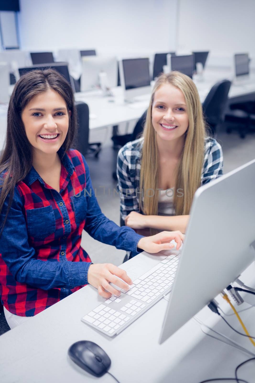 Smiling students using computer at university 